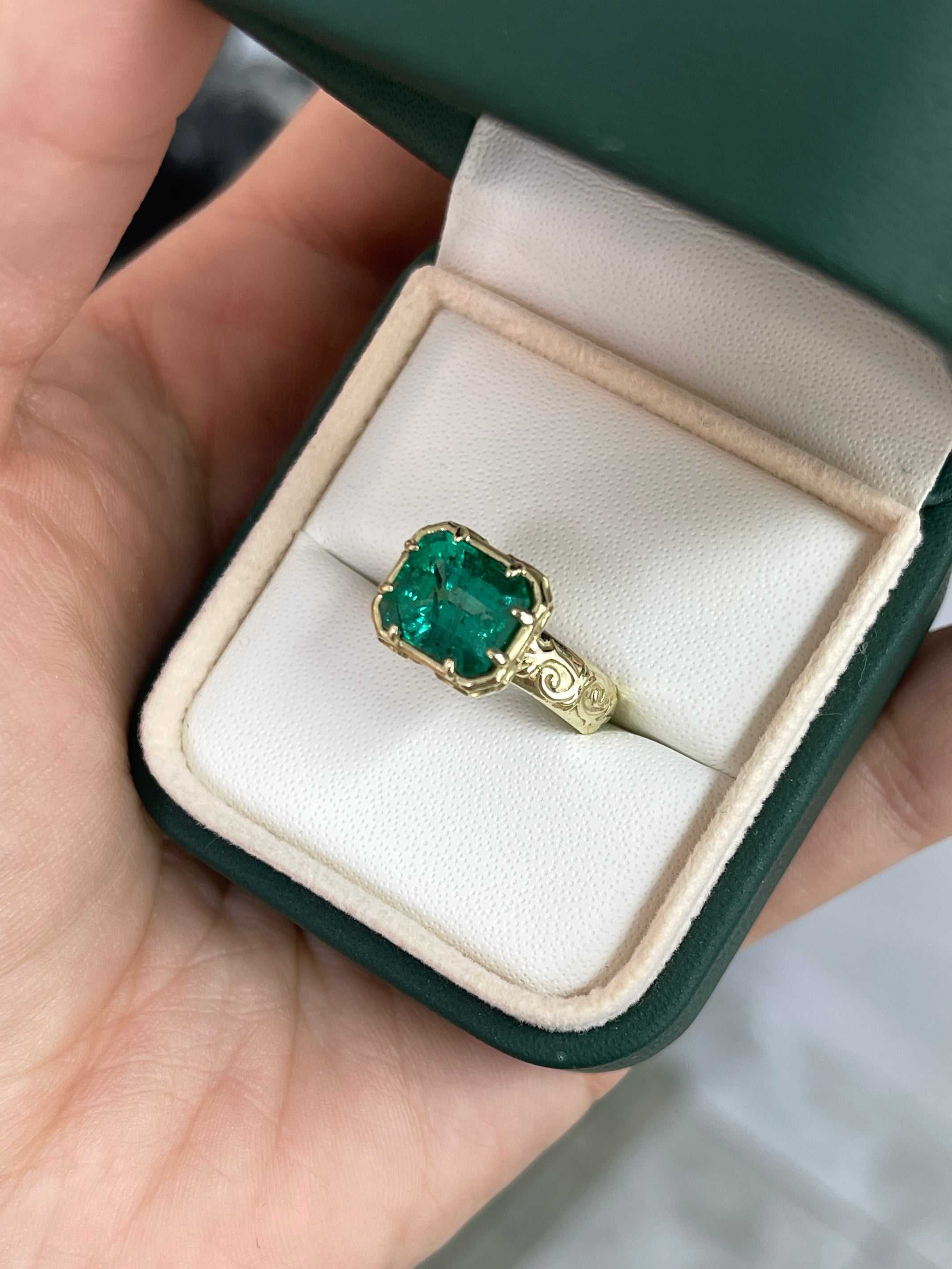 14K gold emerald solitaire ring featuring a 3.65ct east-to-west freckled earth-mined Colombian emerald with scroll and etched gold detailing.