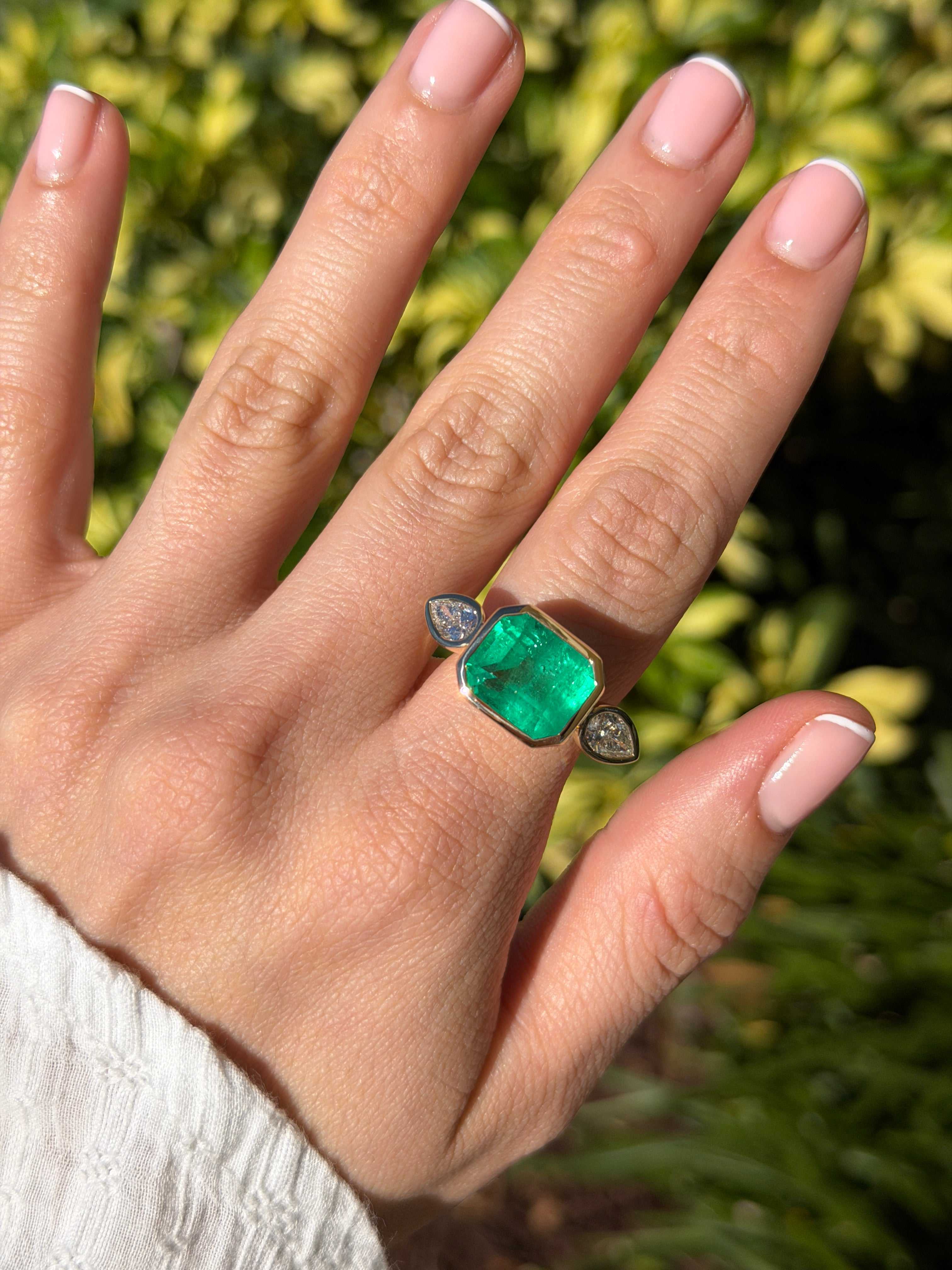 East to West Colombian emerald and pear diamond three-stone ring by JR Colombian Emeralds, 18K gold, showcasing vibrant gemstones.