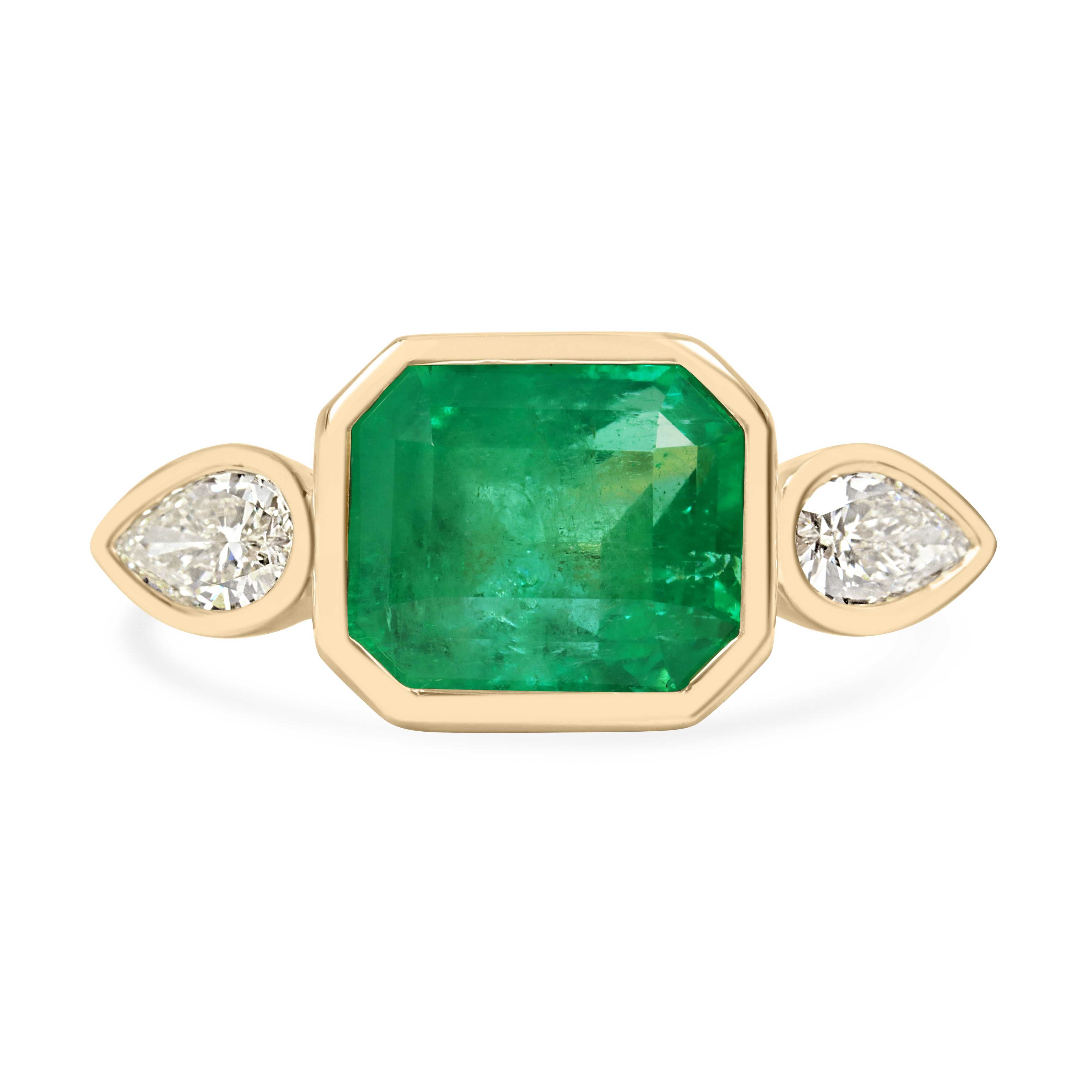 East to West Colombian emerald and pear diamond three-stone ring in 18K gold by JR Colombian Emeralds, showcasing vibrant gemstones.