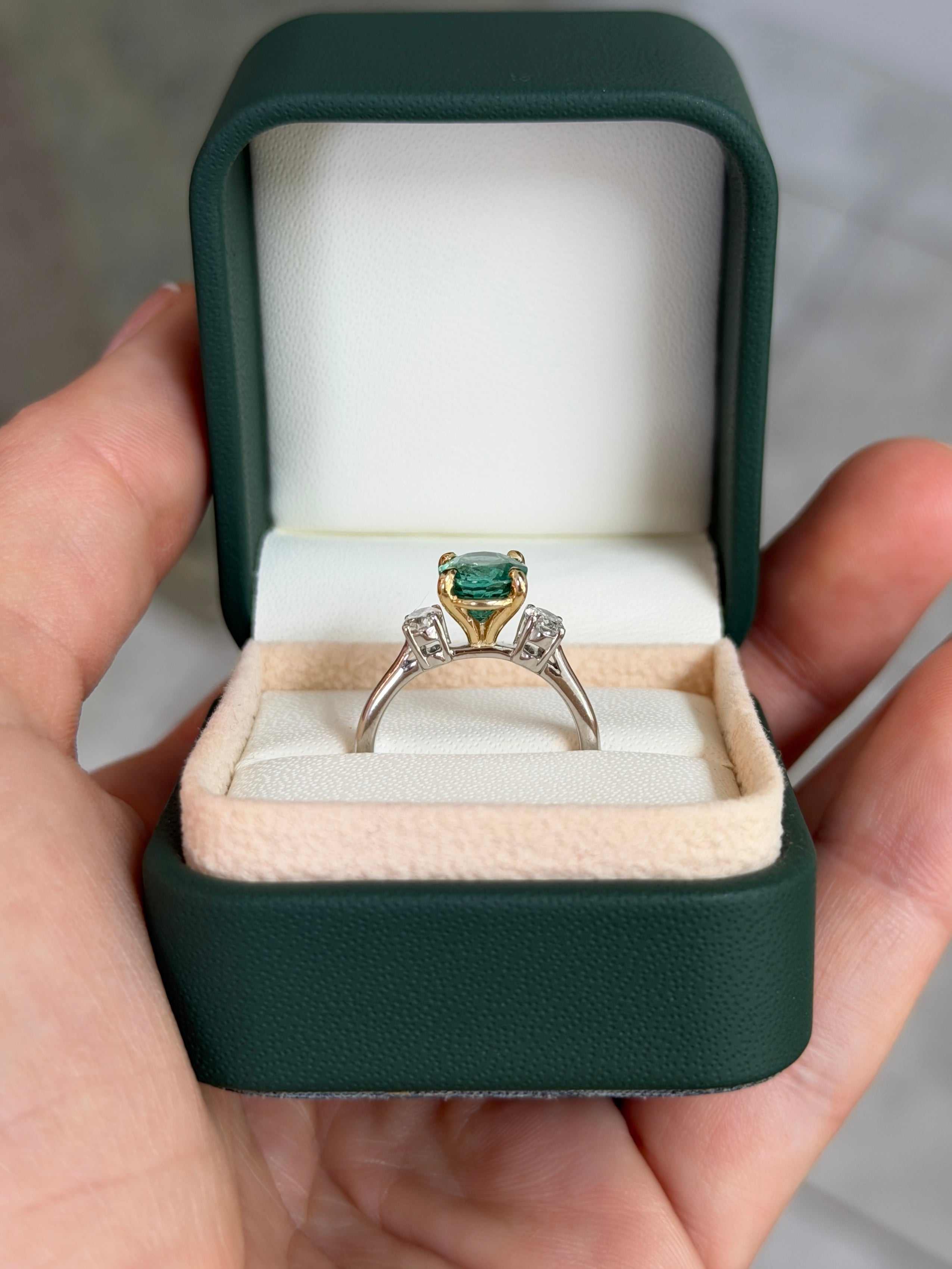 JR Colombian Emeralds three-stone engagement ring with vibrant oval emerald and lab diamond accents in 14K platinum.