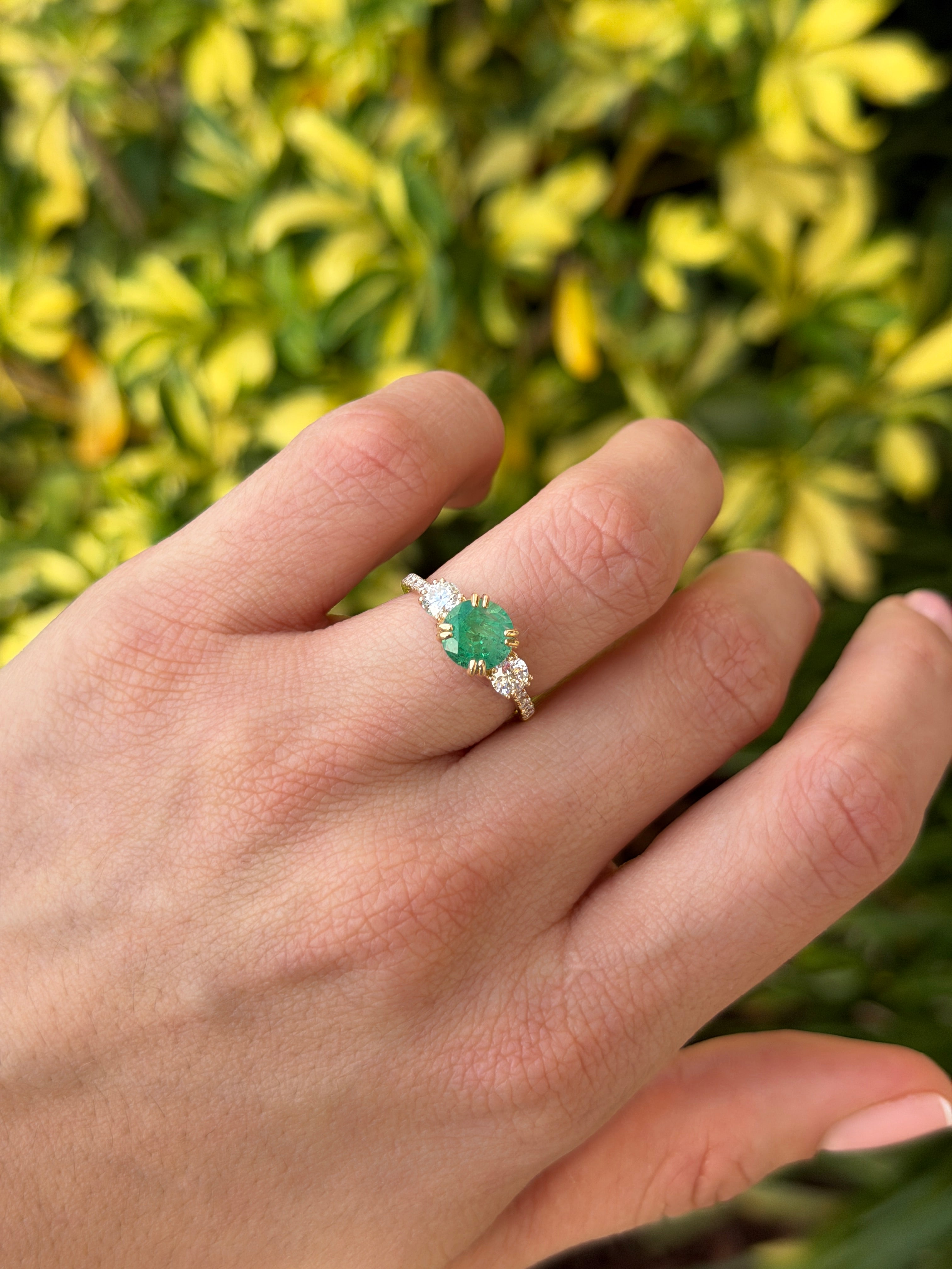 14K natural emerald and lab diamond three-stone engagement ring with accent diamonds, featuring round emeralds and a polished band.
