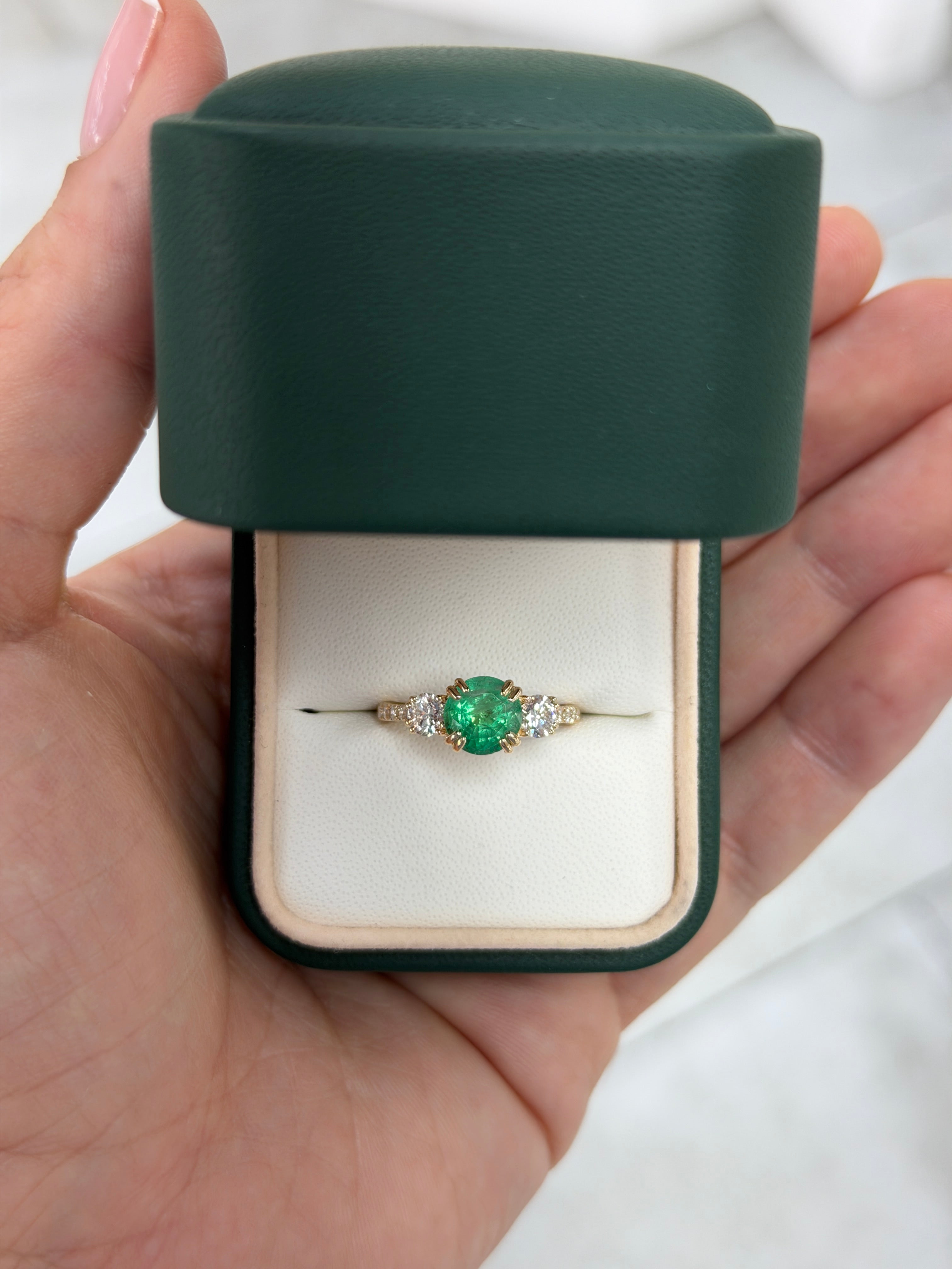 14K gold engagement ring featuring 2.60tcw natural round emeralds and lab diamonds in a three-stone design with accent diamonds.