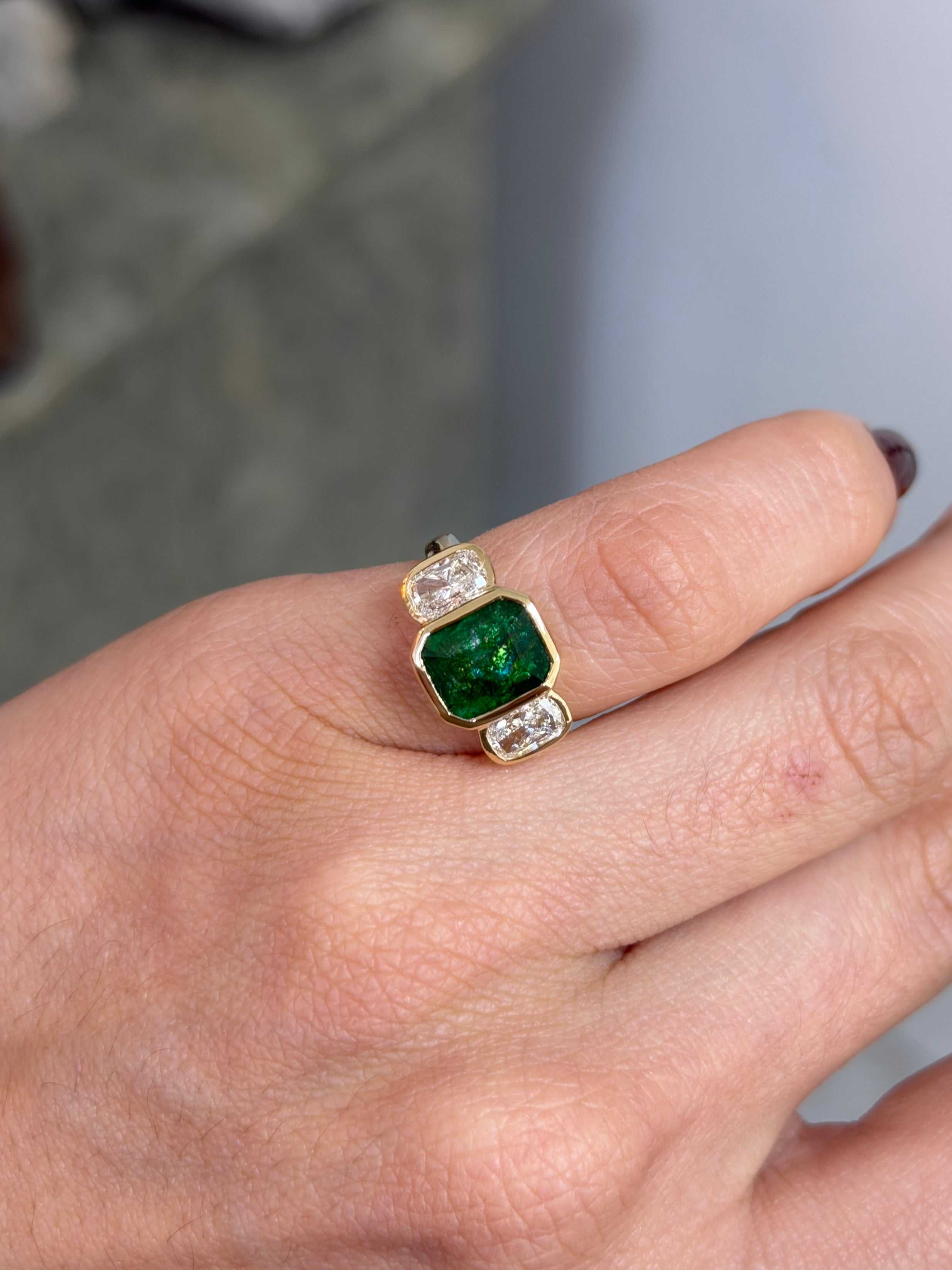 Bezel set emerald and cushion cut lab diamond three stone ring in 14K gold by JR Colombian Emeralds, showcasing sparkling gemstones.