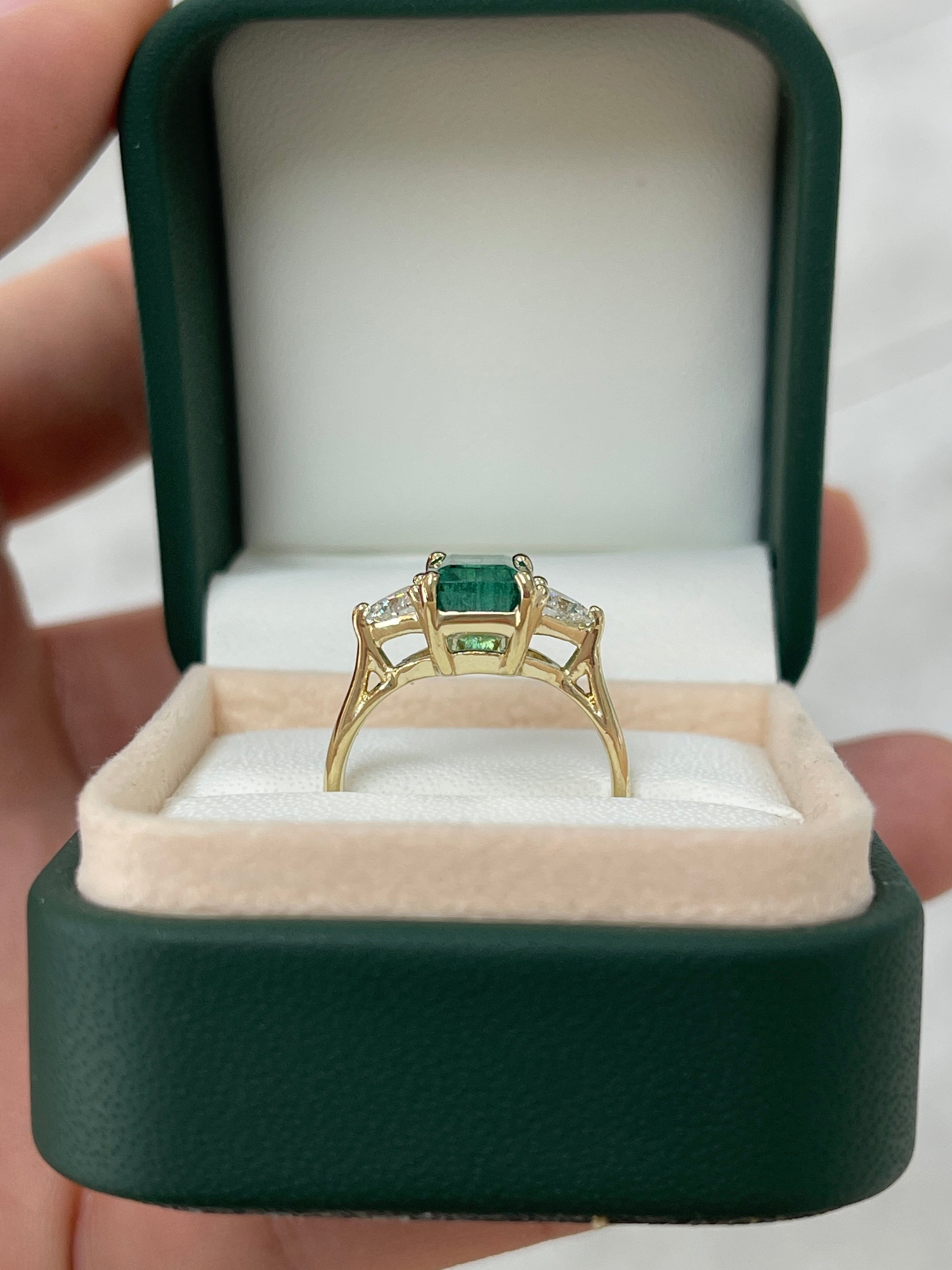 Three stone ring featuring natural emerald and lab diamond trillion cuts in 14K gold, showcasing sparkling gemstones and intricate design.