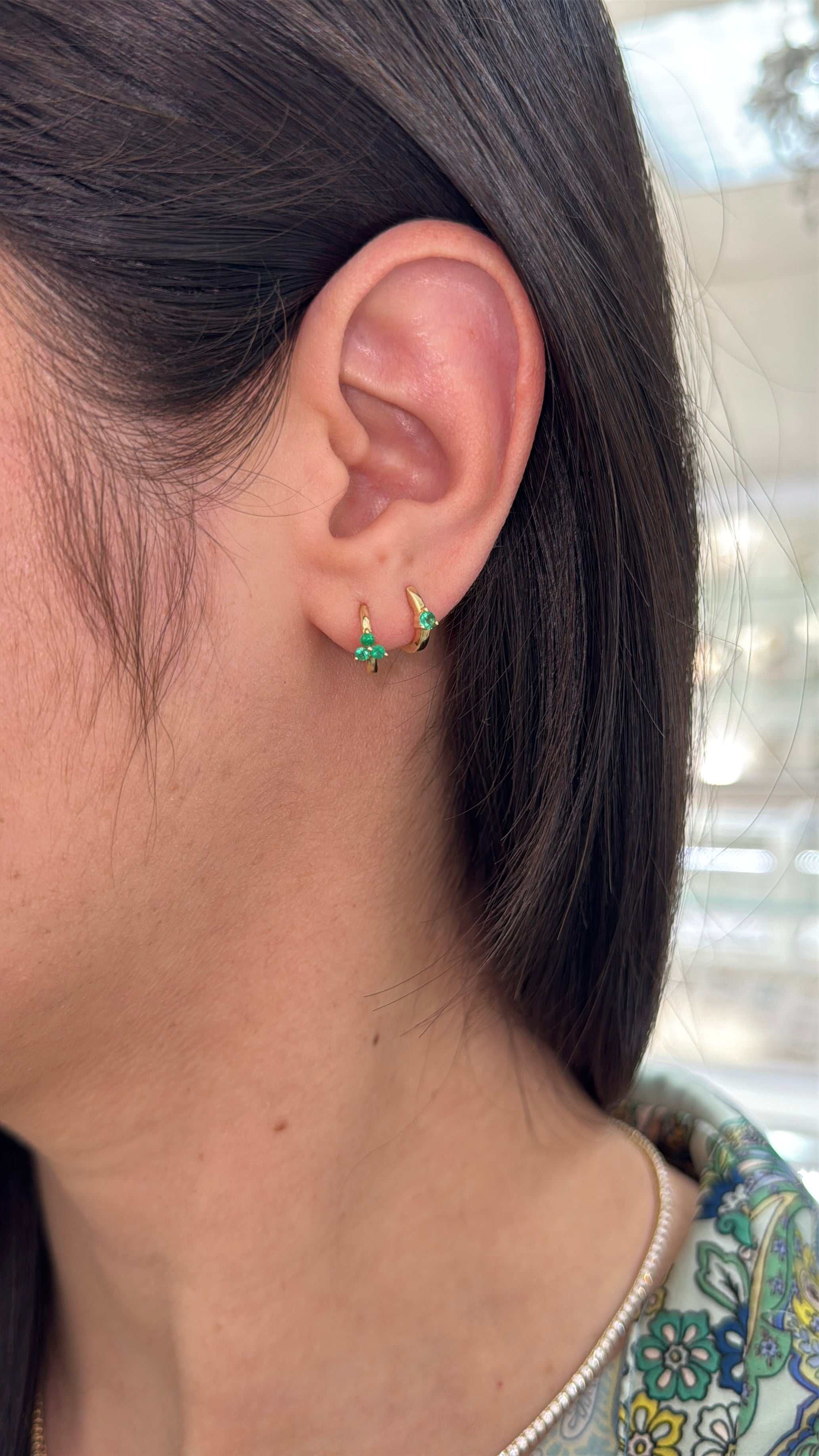 Emerald huggie earring with three-prong setting in 14K gold, featuring a vibrant green emerald gemstone.