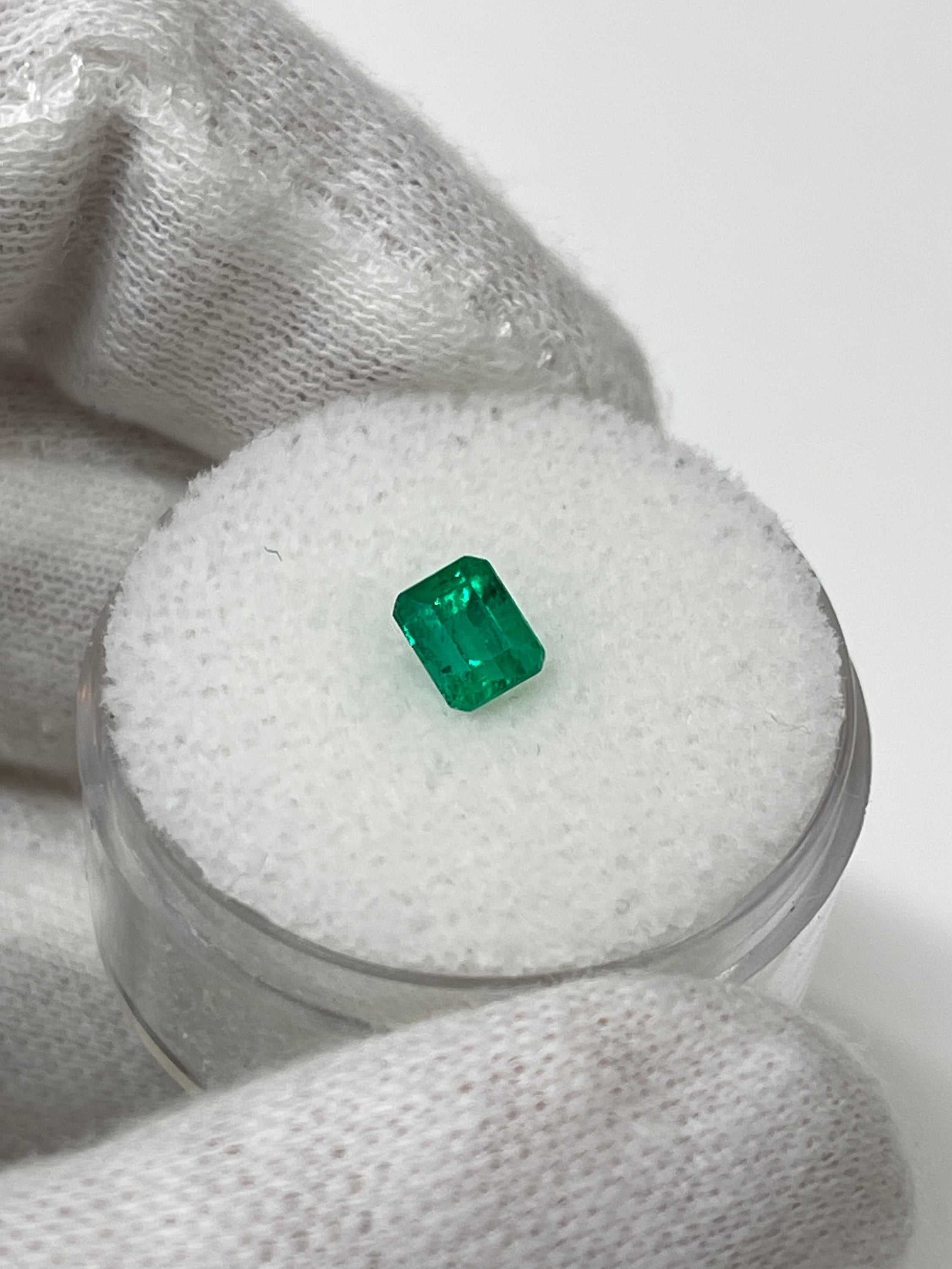Loose 0.62 carat Colombian emerald cut gemstone with AAA+ clarity, showcasing vibrant green color and fine craftsmanship.