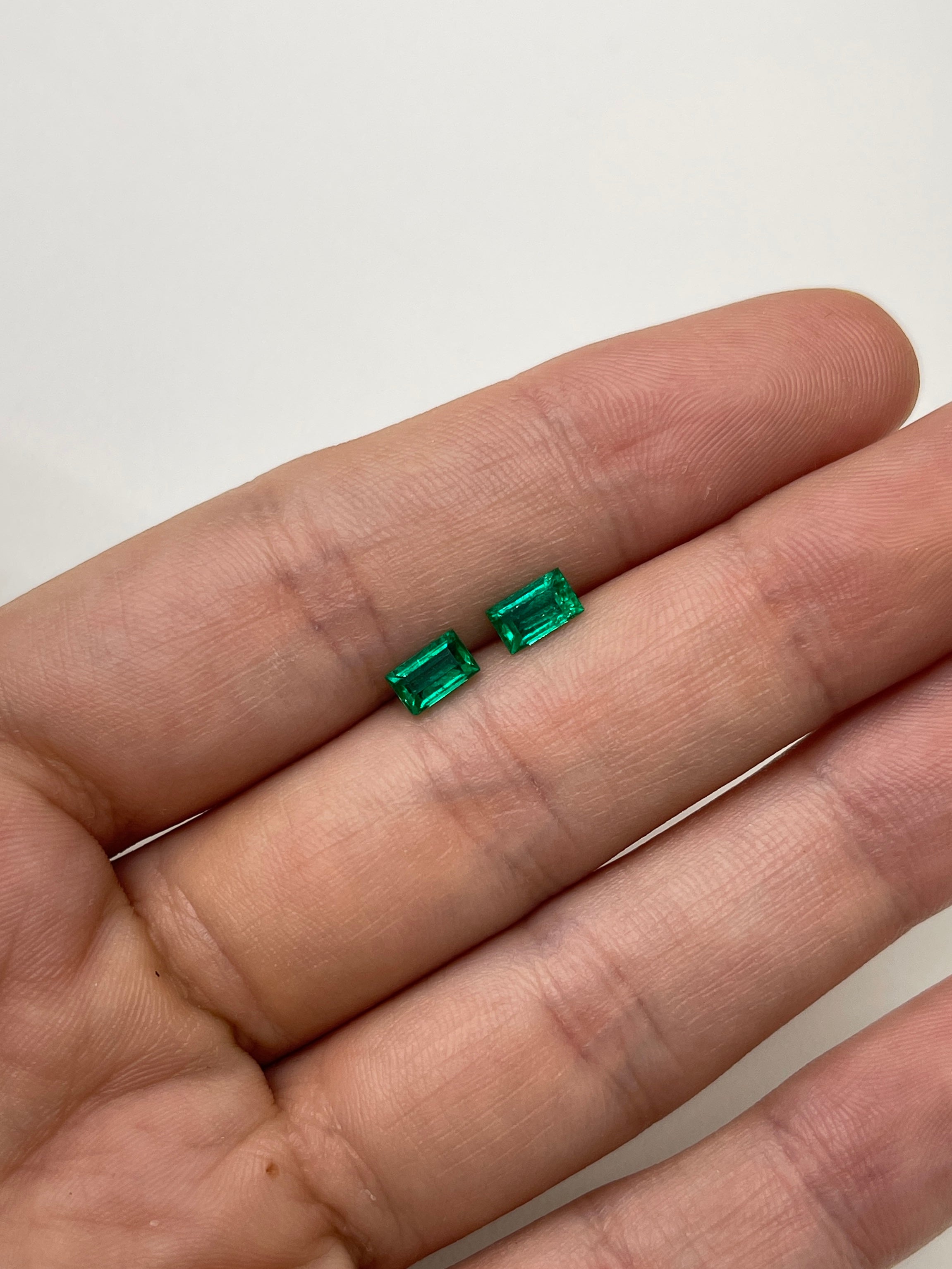 Matching pair of green Colombian emeralds, baguette cut, 0.99tcw, showcasing natural brilliance and vibrant color.