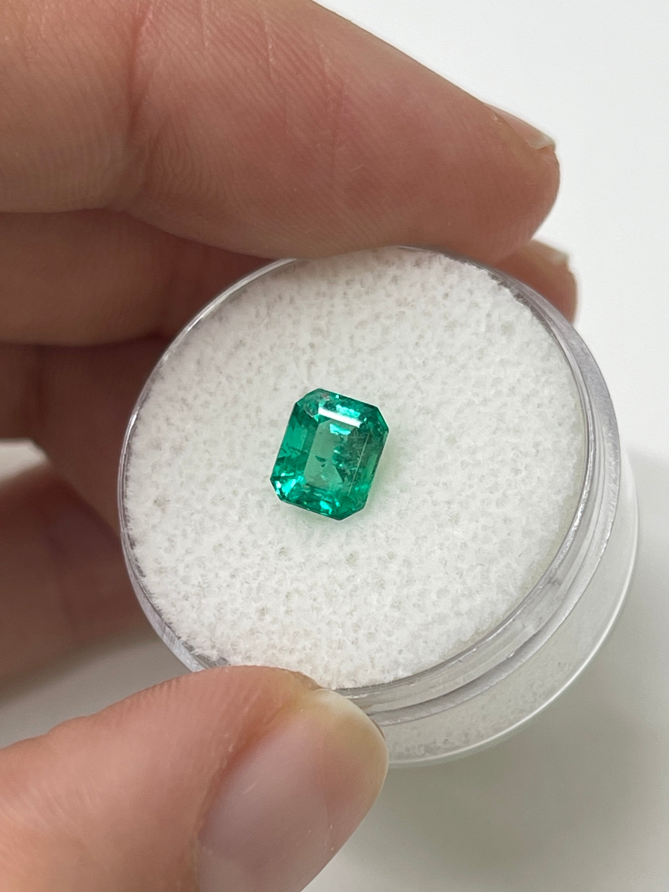 1.22 carat bluish green natural Colombian emerald loose stone in emerald cut, showcasing vibrant color and clarity.