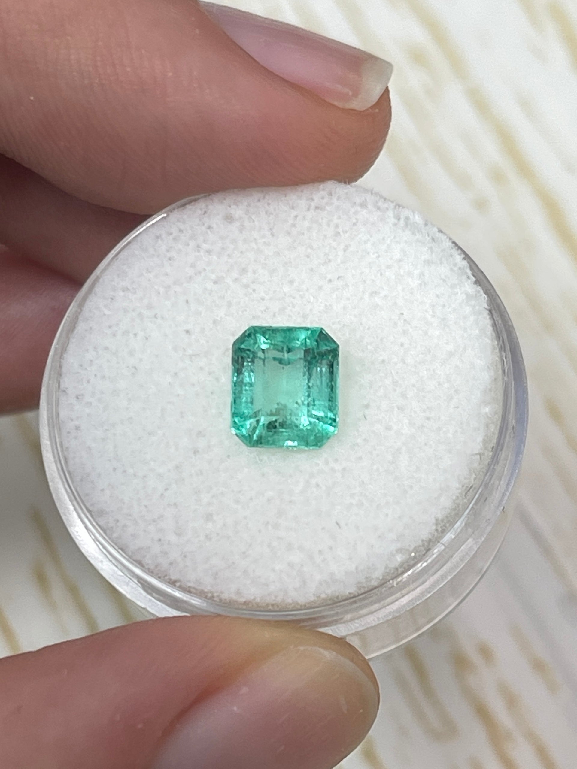 Natural 1.59 carat pastel green Colombian emerald loose gemstone in an emerald cut, showcasing vibrant color and clarity.