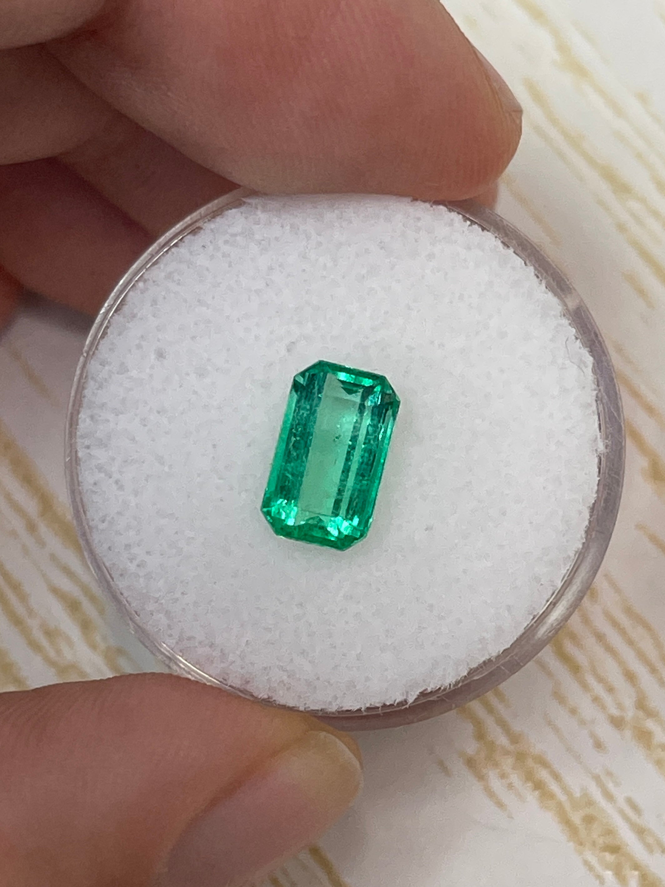 Natural 1.68 carat yellowish green Colombian emerald loose gemstone in an emerald cut, displayed for jewelry use.