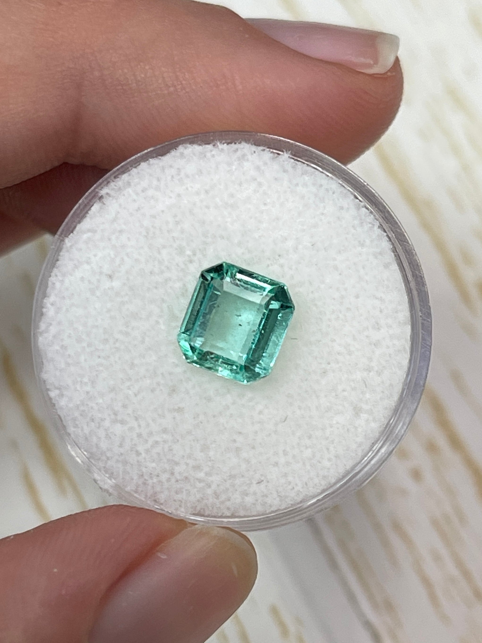 Loose 1.74 carat Colombian emerald with freckled portrait and Asscher cut, showcasing vibrant green color and natural inclusions.