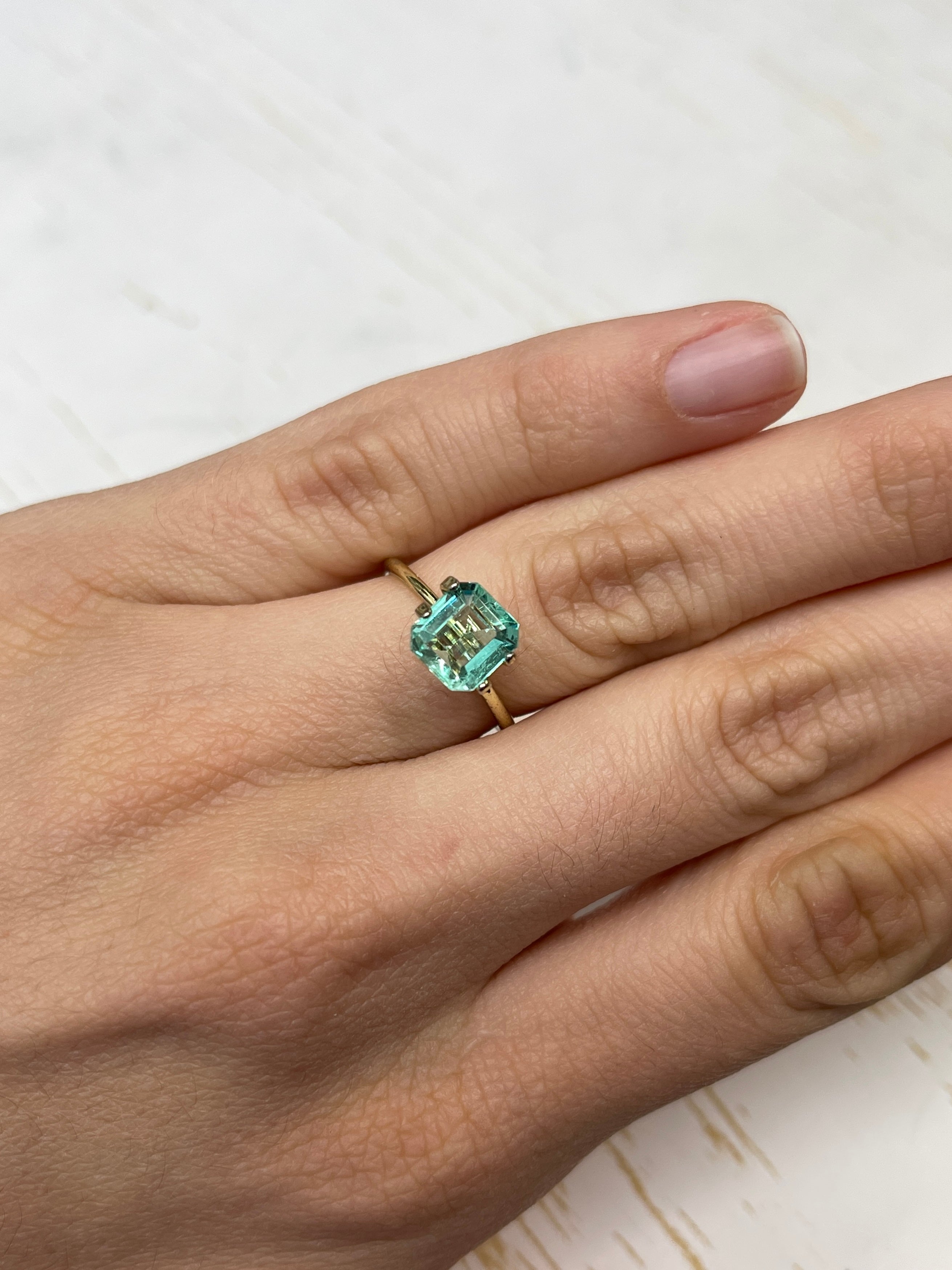 1.74 carat freckled Colombian emerald in Asscher cut, loose gemstone with vibrant green color and distinctive portrait cut facets.