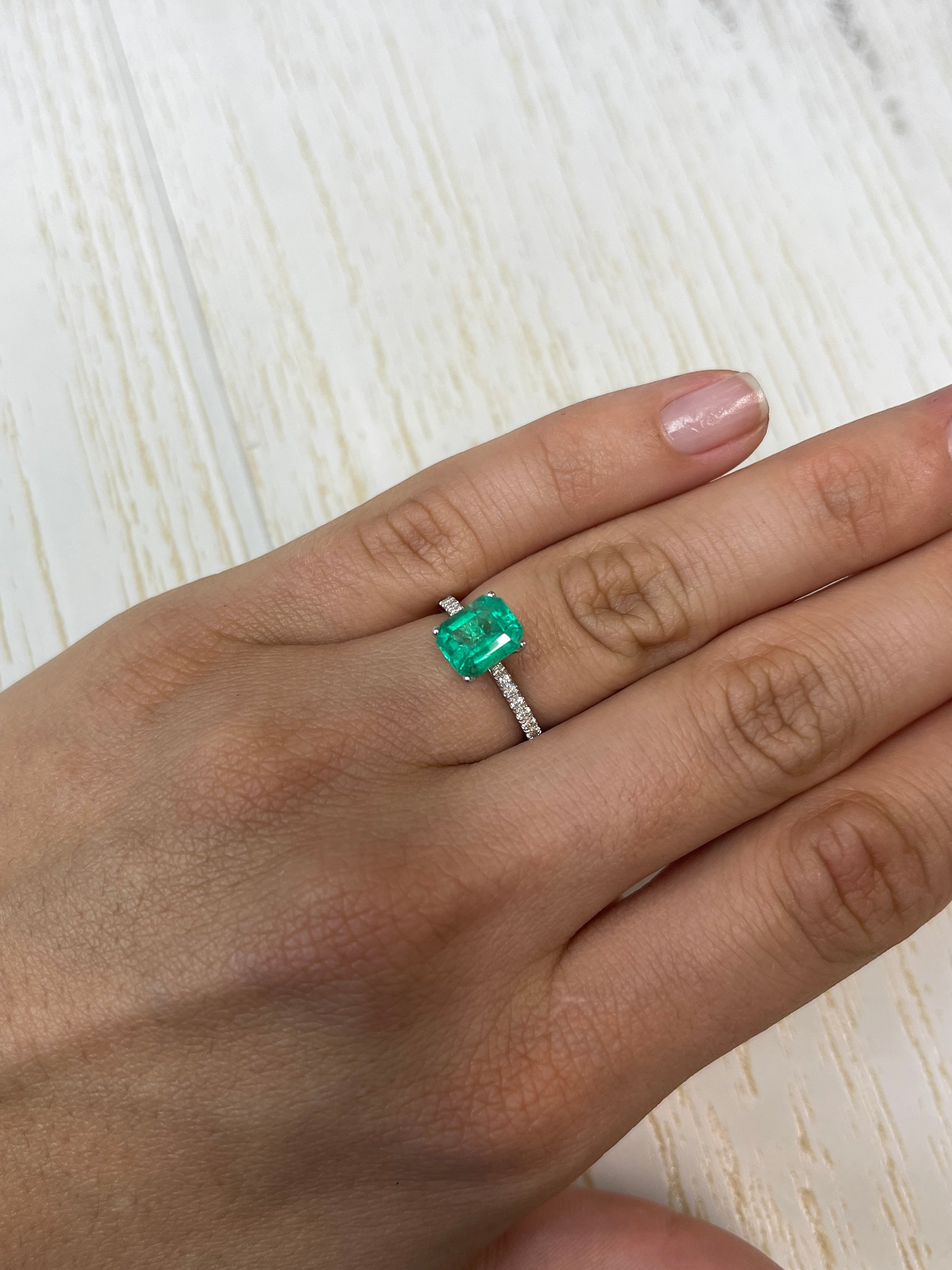 1.94 carat freckled green Colombian emerald loose gemstone in emerald cut, showcasing natural color and unique inclusions.