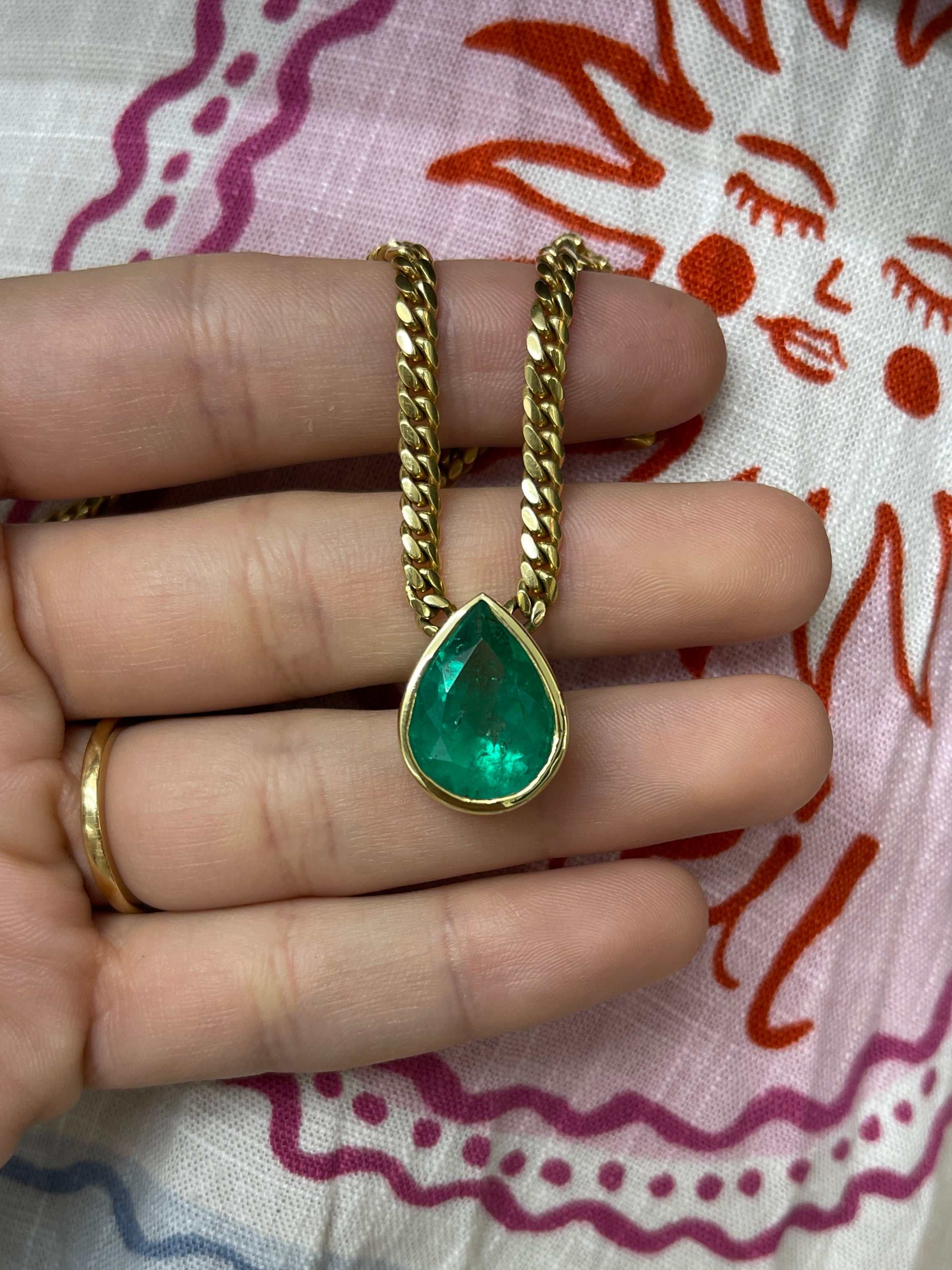 Vivid 10.80ct pear-cut Colombian emerald bezel-set Cuban link necklace by JR Colombian Emeralds, showcasing lush green stones.