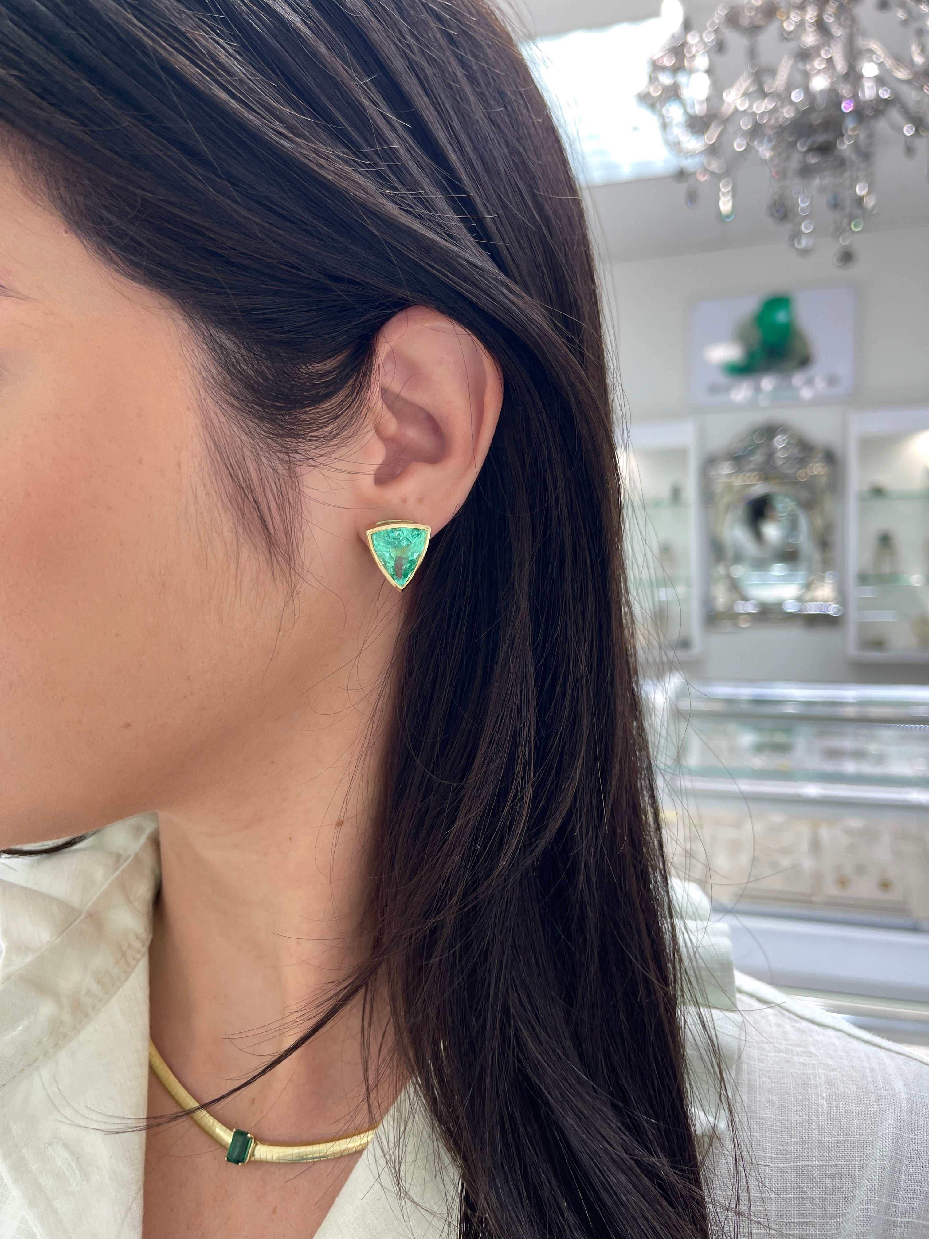 15.76tcw rare large trillion cut Colombian emerald bezel set 18K gold earrings worn on ear