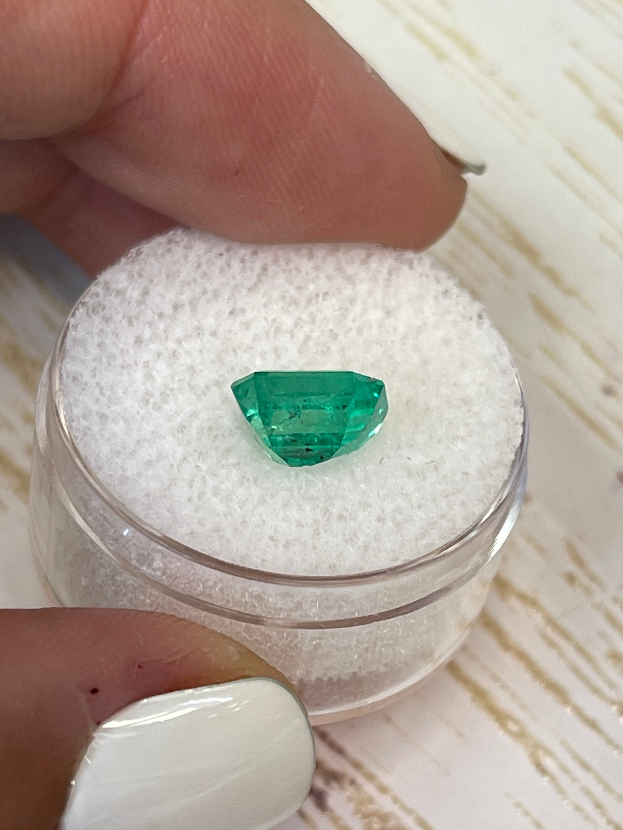 Freckled bluish-green 2.12 carat Colombian emerald loose gemstone in emerald cut, showcasing natural color and unique inclusions.