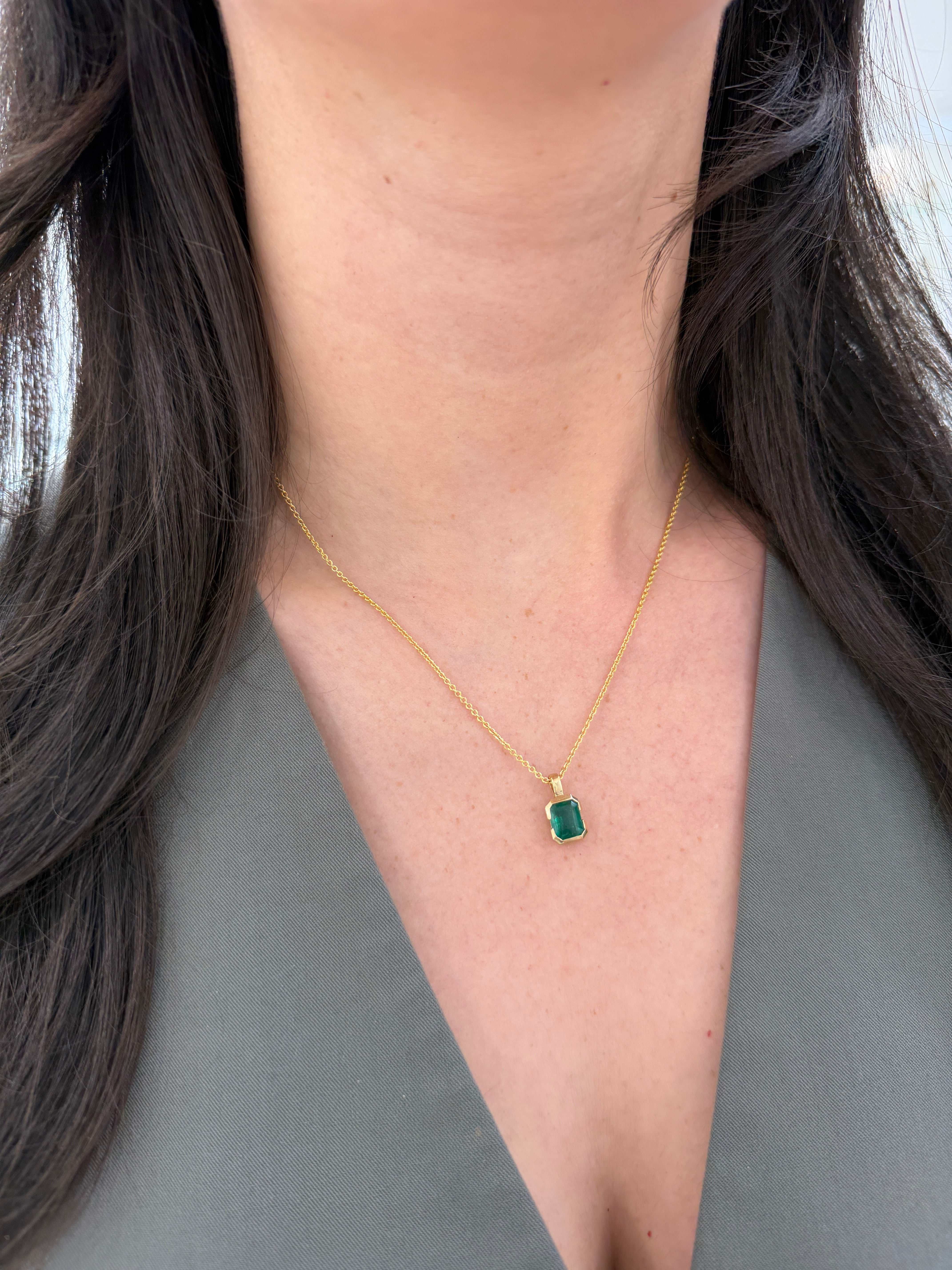 14K gold emerald solitaire necklace with 2.28 carat semi bezel emerald pendant touching the skin, by JR Colombian Emeralds.