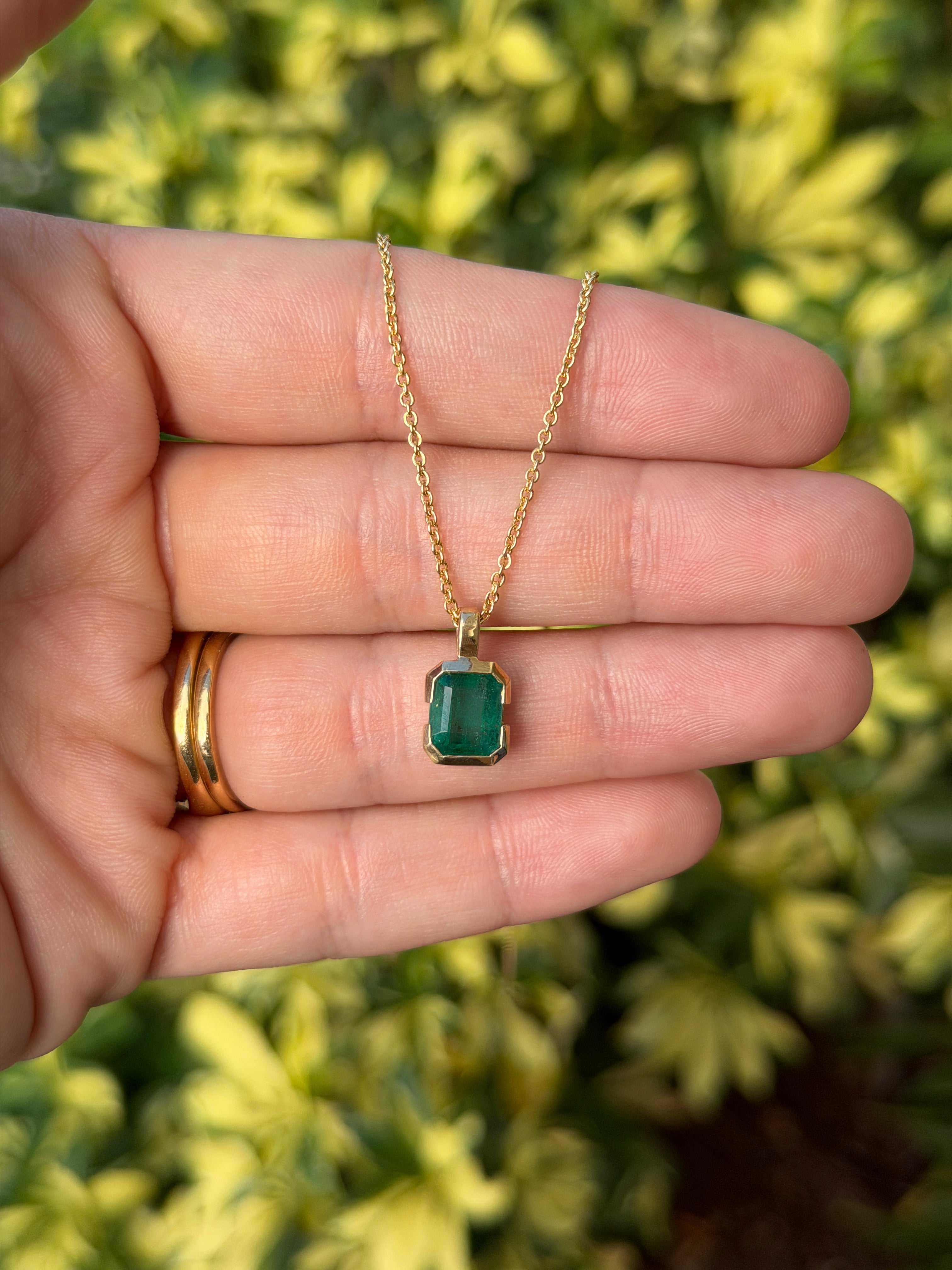 2.28 Carat semi-bezel emerald solitaire necklace in 14K gold by JR Colombian Emeralds, featuring a vibrant emerald touch against skin.