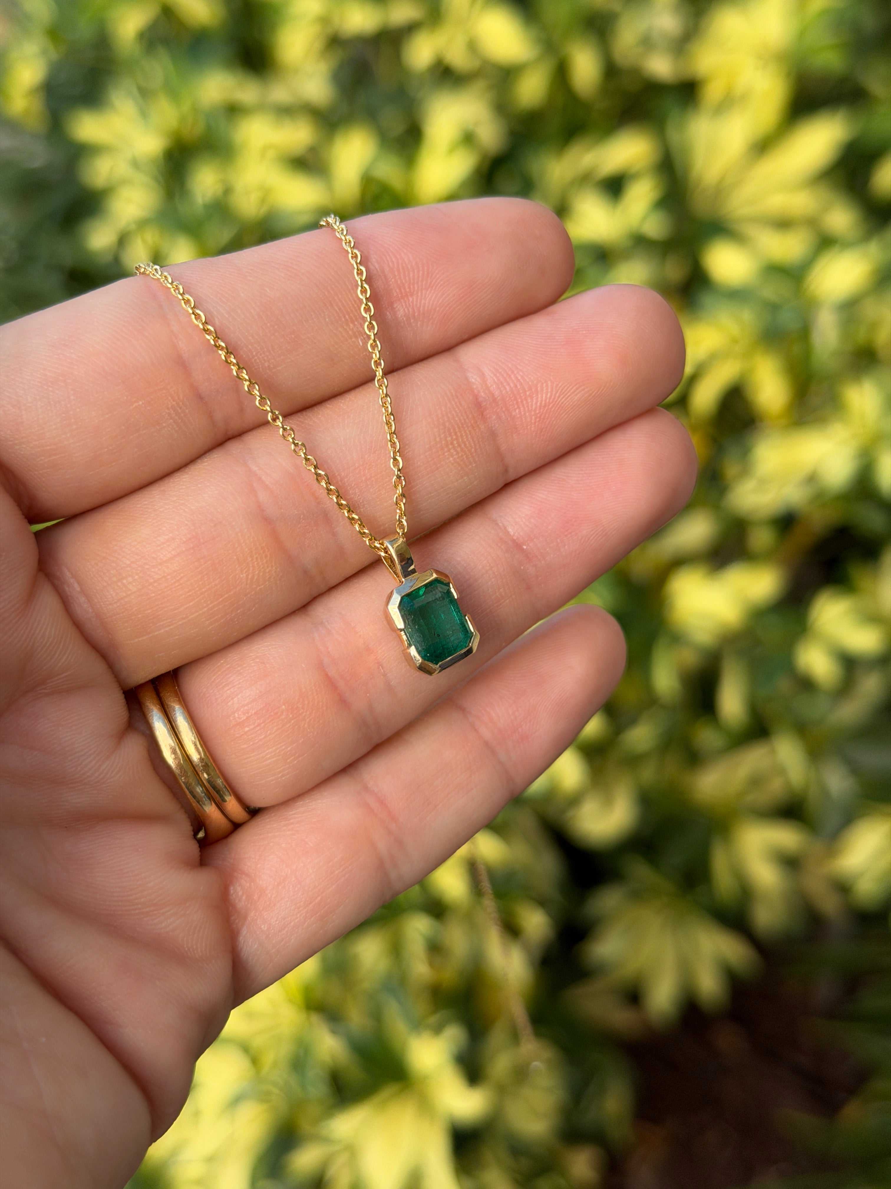 14K gold emerald solitaire necklace featuring a 2.28 carat semi-bezel emerald pendant touching the skin, by JR Colombian Emeralds.