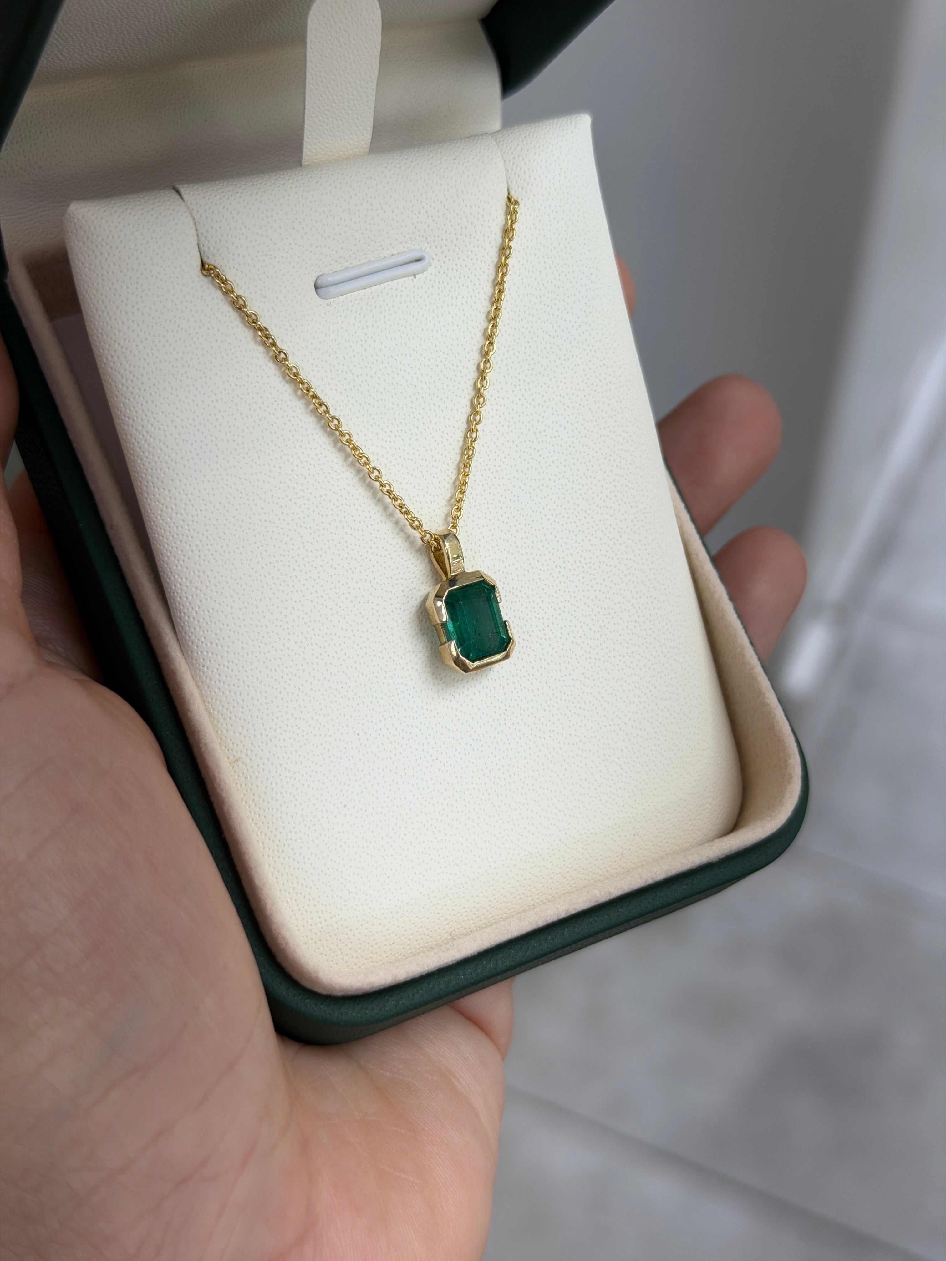 14K gold emerald solitaire necklace featuring a 2.28 carat semi-bezel emerald pendant on skin-touching chain.