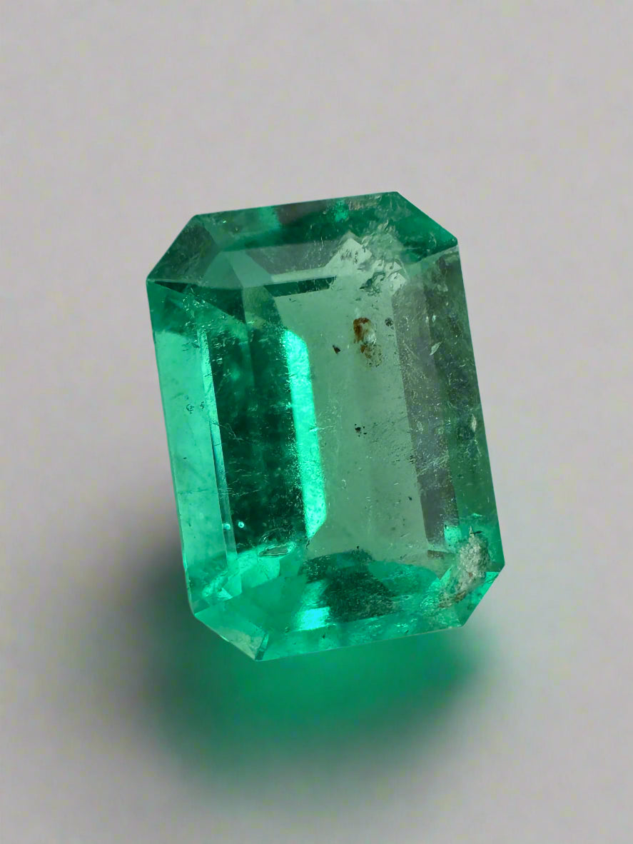 Freckled 2.31 carat medium green Colombian emerald cut emerald from JR Colombian Emeralds, showcasing its vibrant color and unique inclusions.