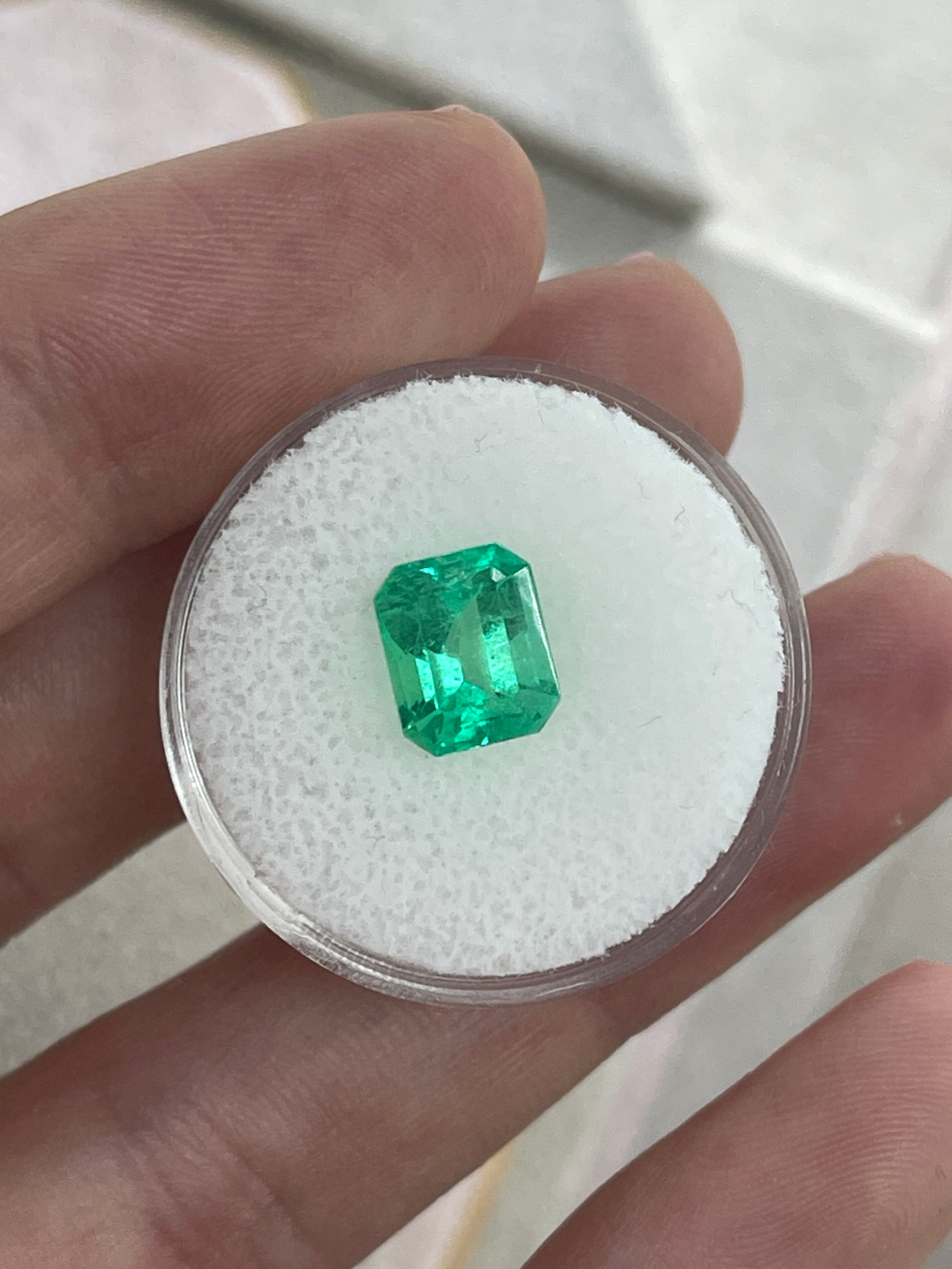 2.47 carat yellowish green natural Colombian emerald loose gemstone in emerald cut, showing clarity and vibrant color.