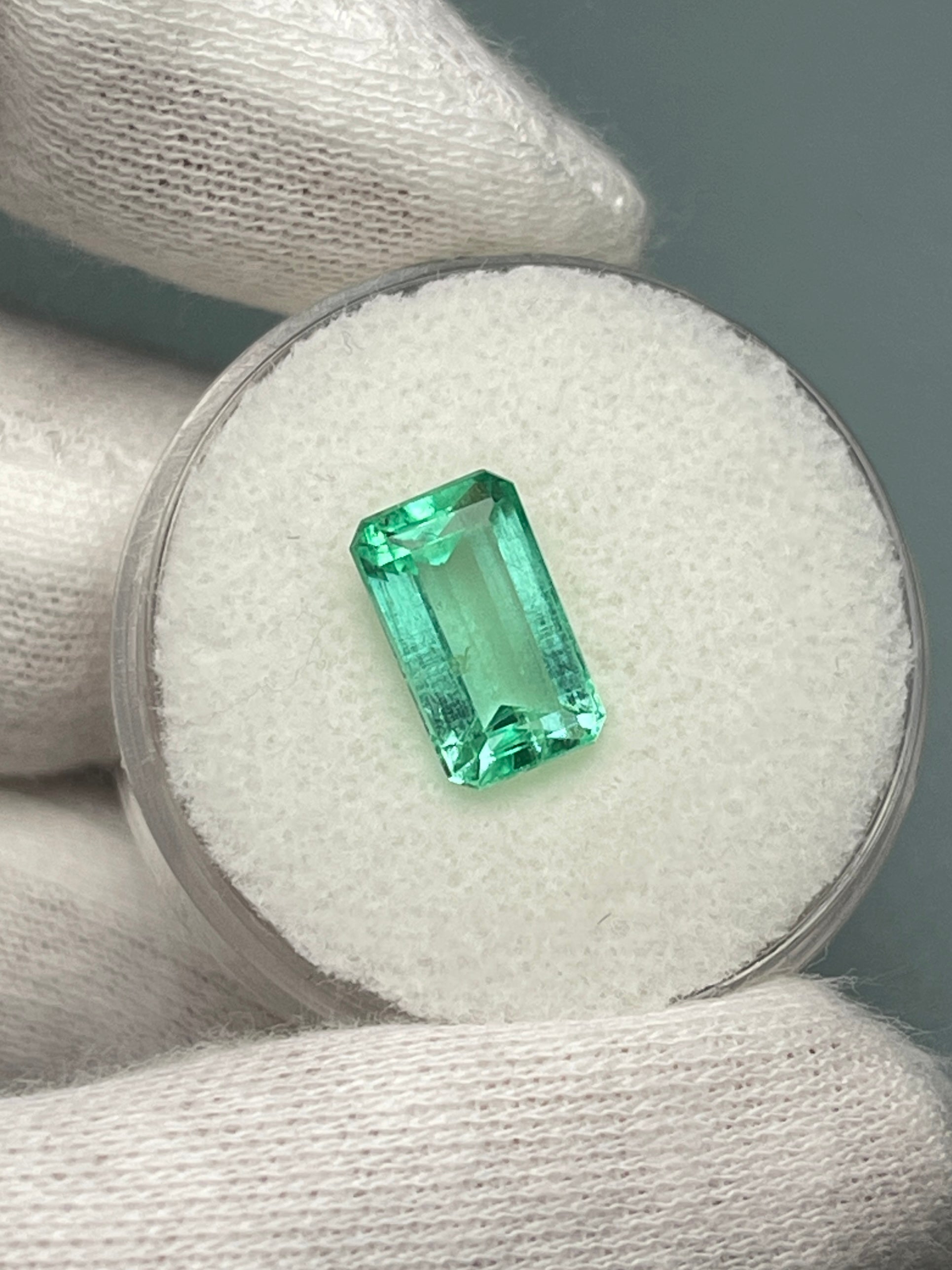 Loose 2.64 carat pastel yellowish green Colombian emerald in an emerald cut, displayed by JR Colombian Emeralds.