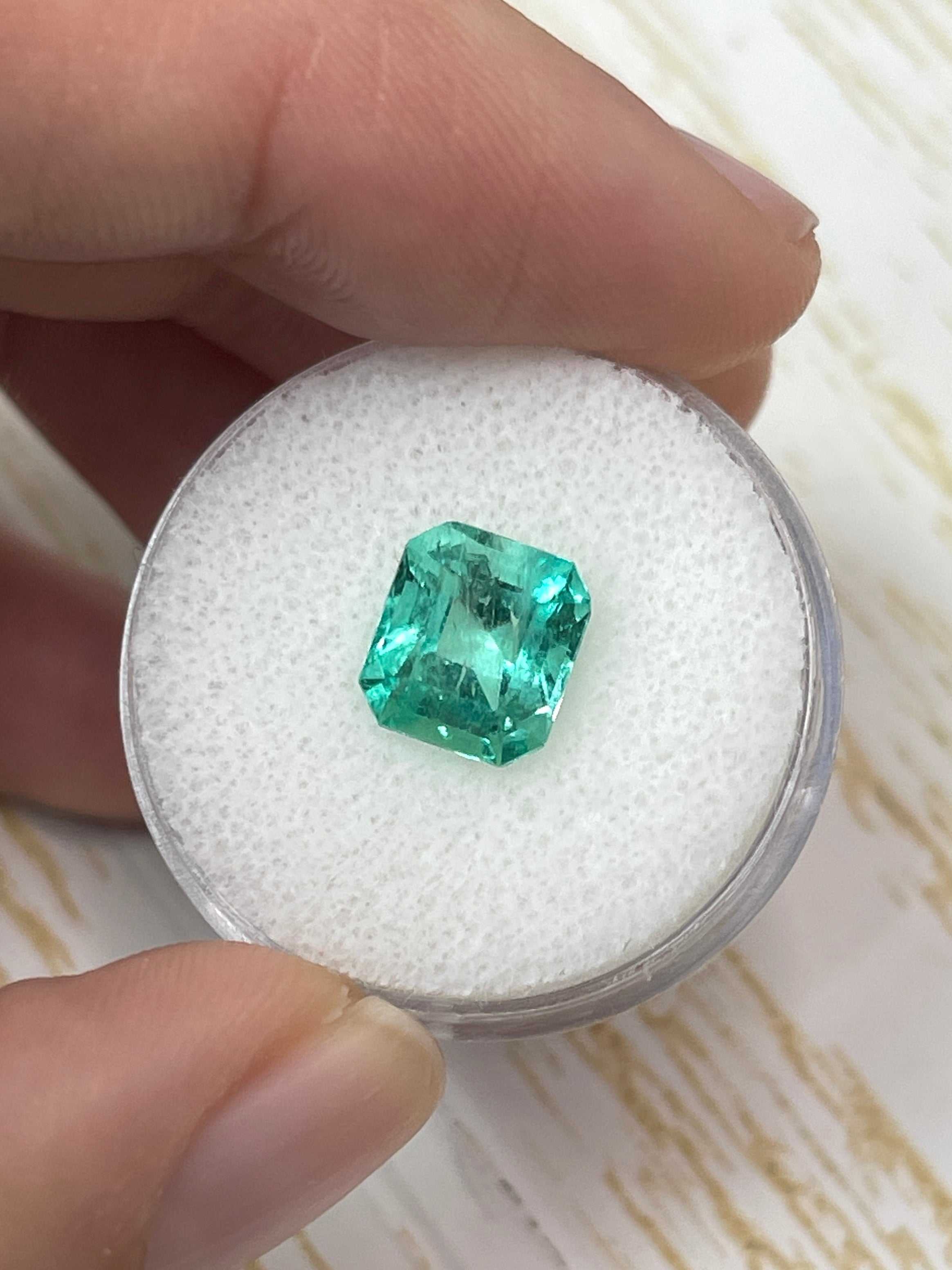 Loose 2.73 carat Colombian emerald in emerald cut with medium green color, set beside a custom lab diamond solitaire engagement ring.