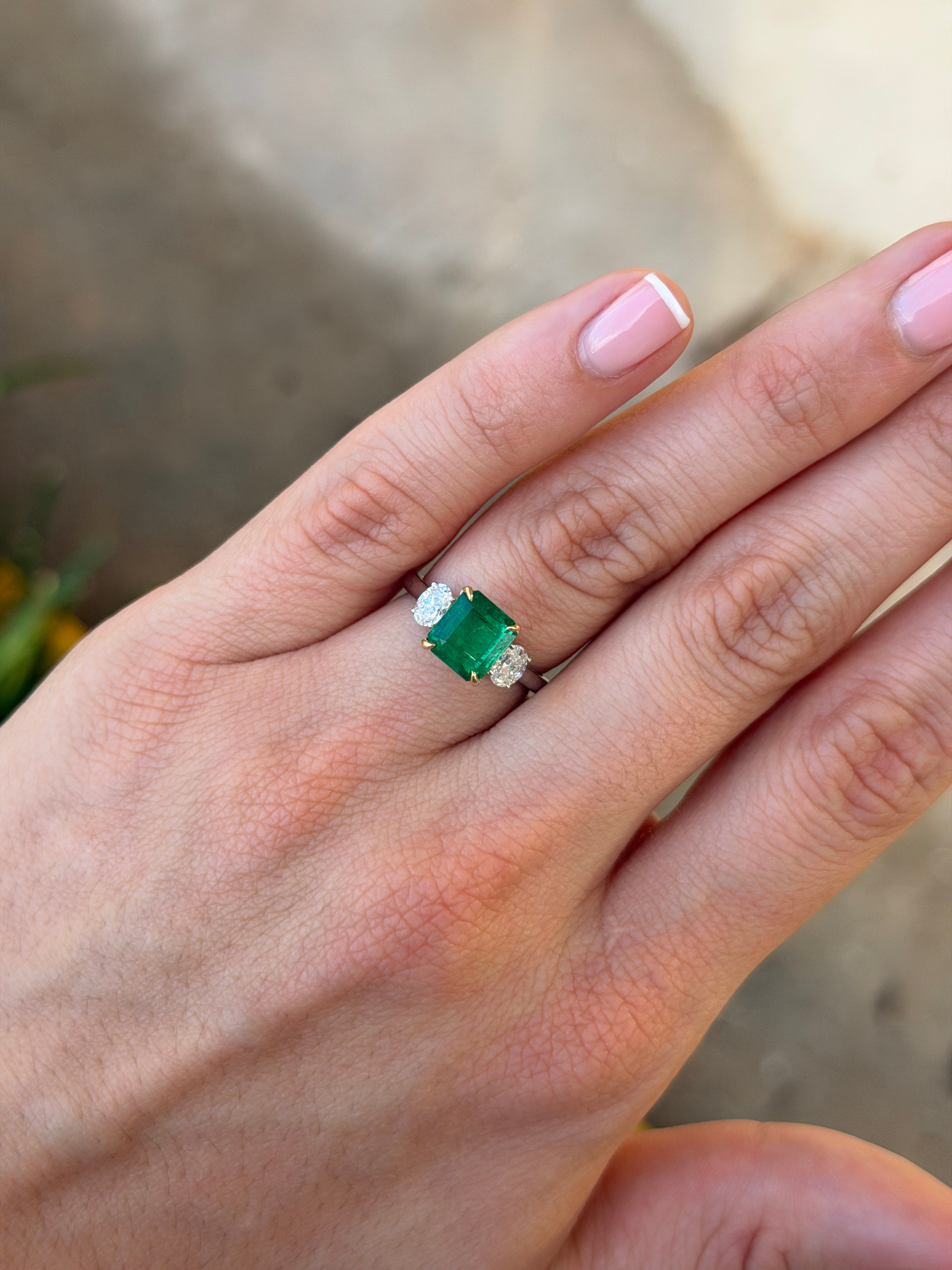 18K gold three-stone ring with vivid asscher cut Colombian emerald and oval diamonds, featuring platinum accents by JR Colombian Emeralds.