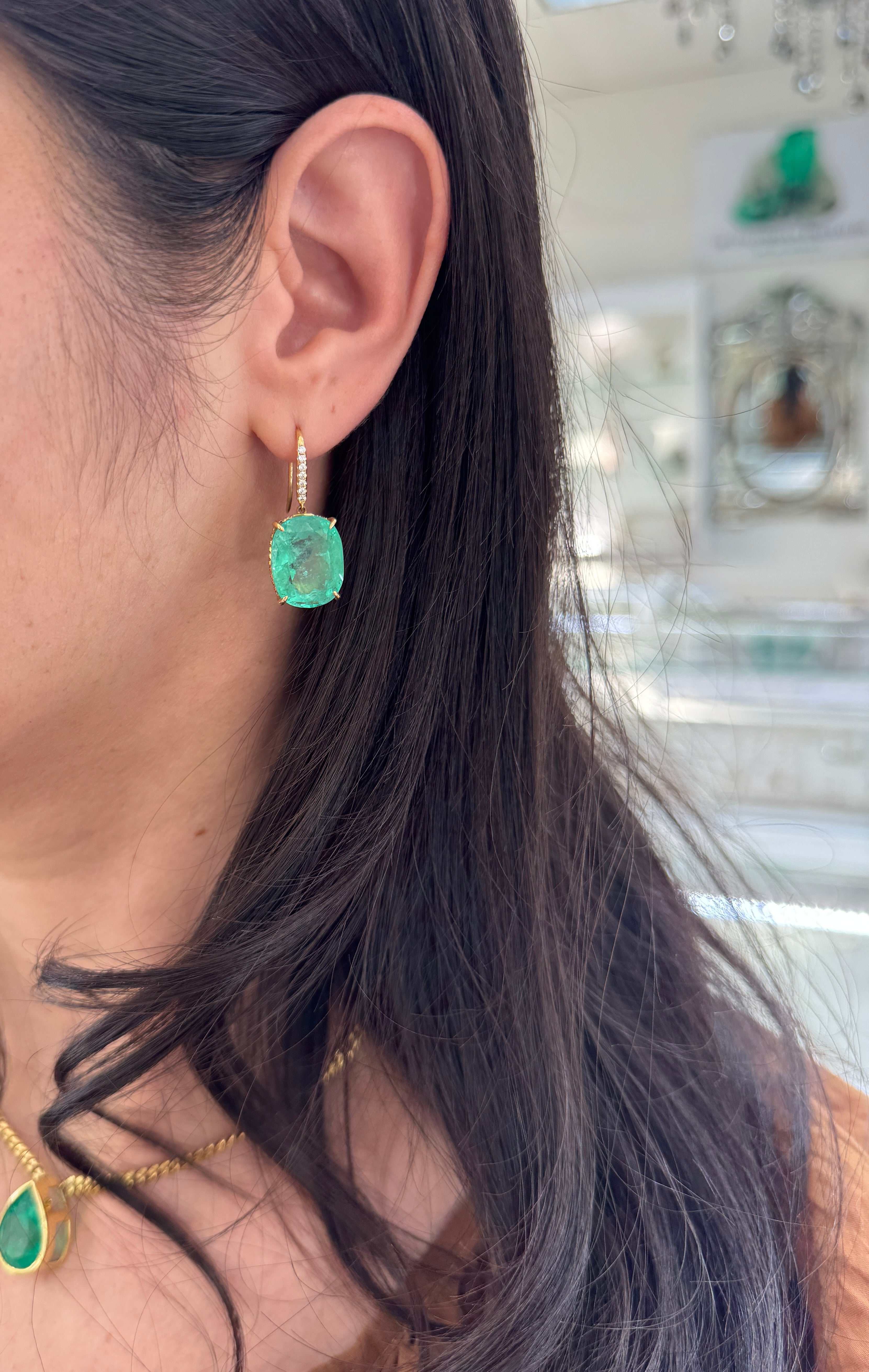 Large cushion cut Colombian emerald and diamond dangle earrings in 18K gold, featuring vibrant green emeralds and sparkling diamonds.