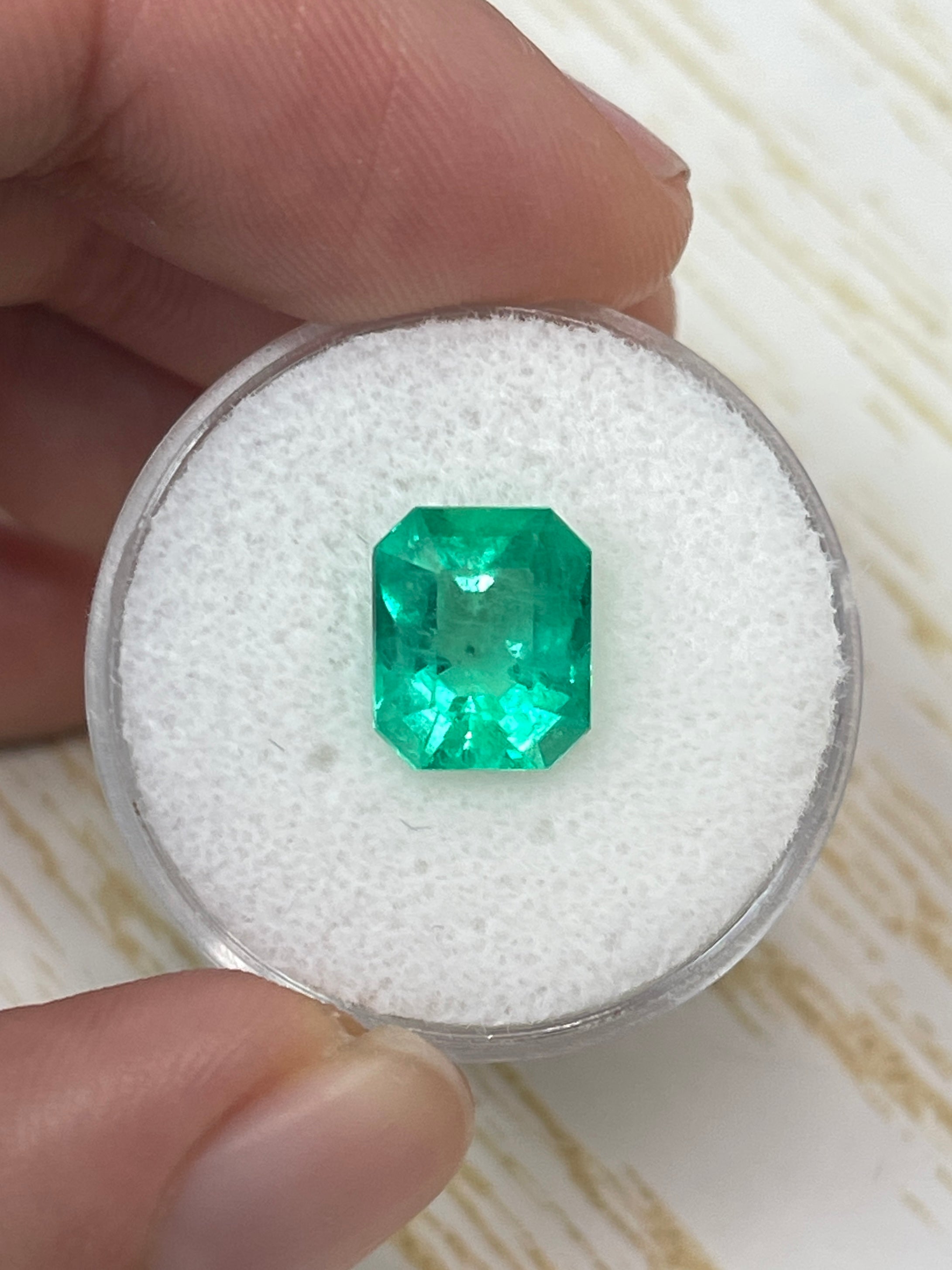Electric yellowish 3.09 carat Colombian emerald in classic emerald cut, displayed by JR Colombian Emeralds.