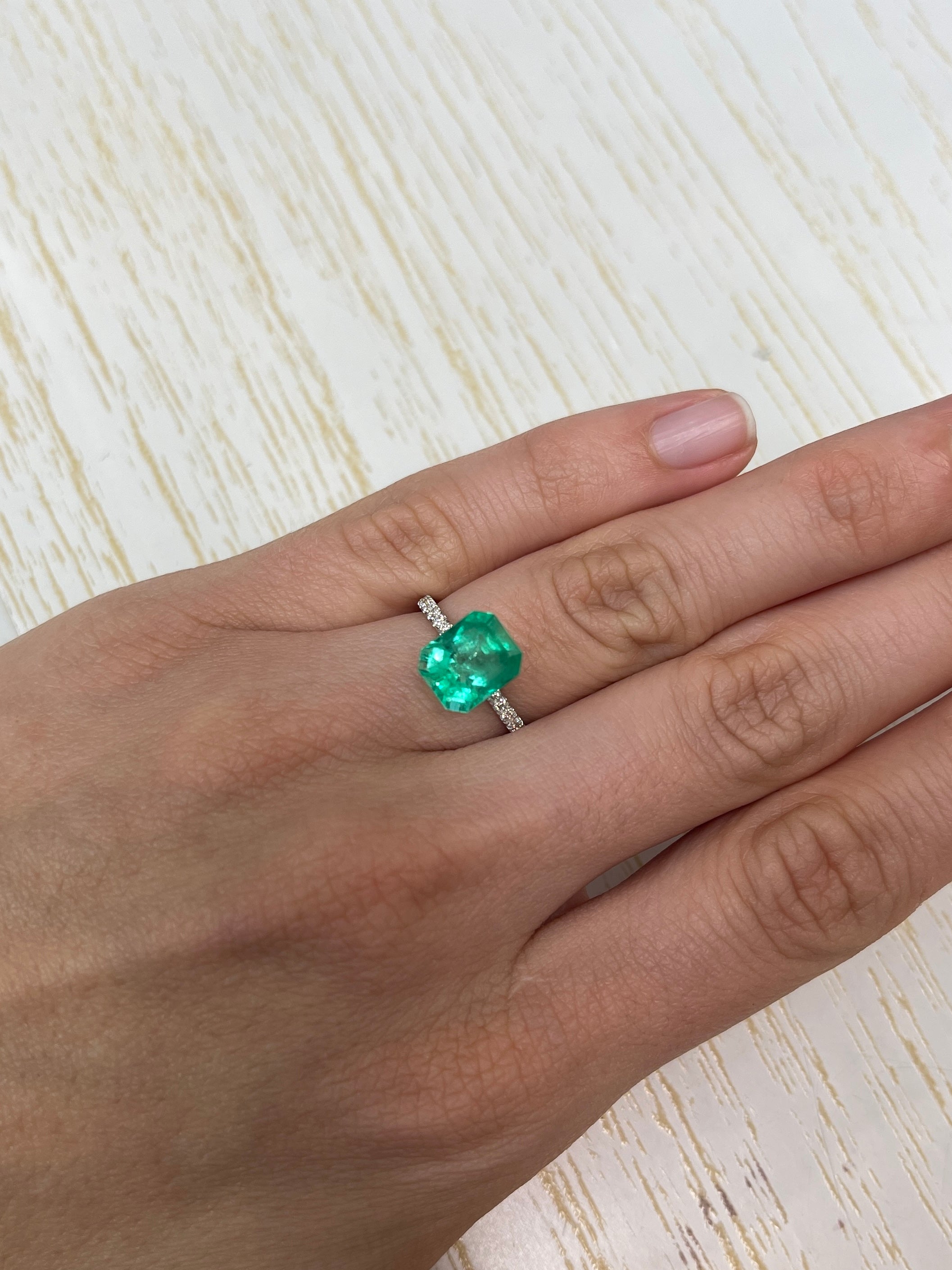 Electric yellowish 3.09 carat Colombian emerald in classic emerald cut, displayed by JR Colombian Emeralds.