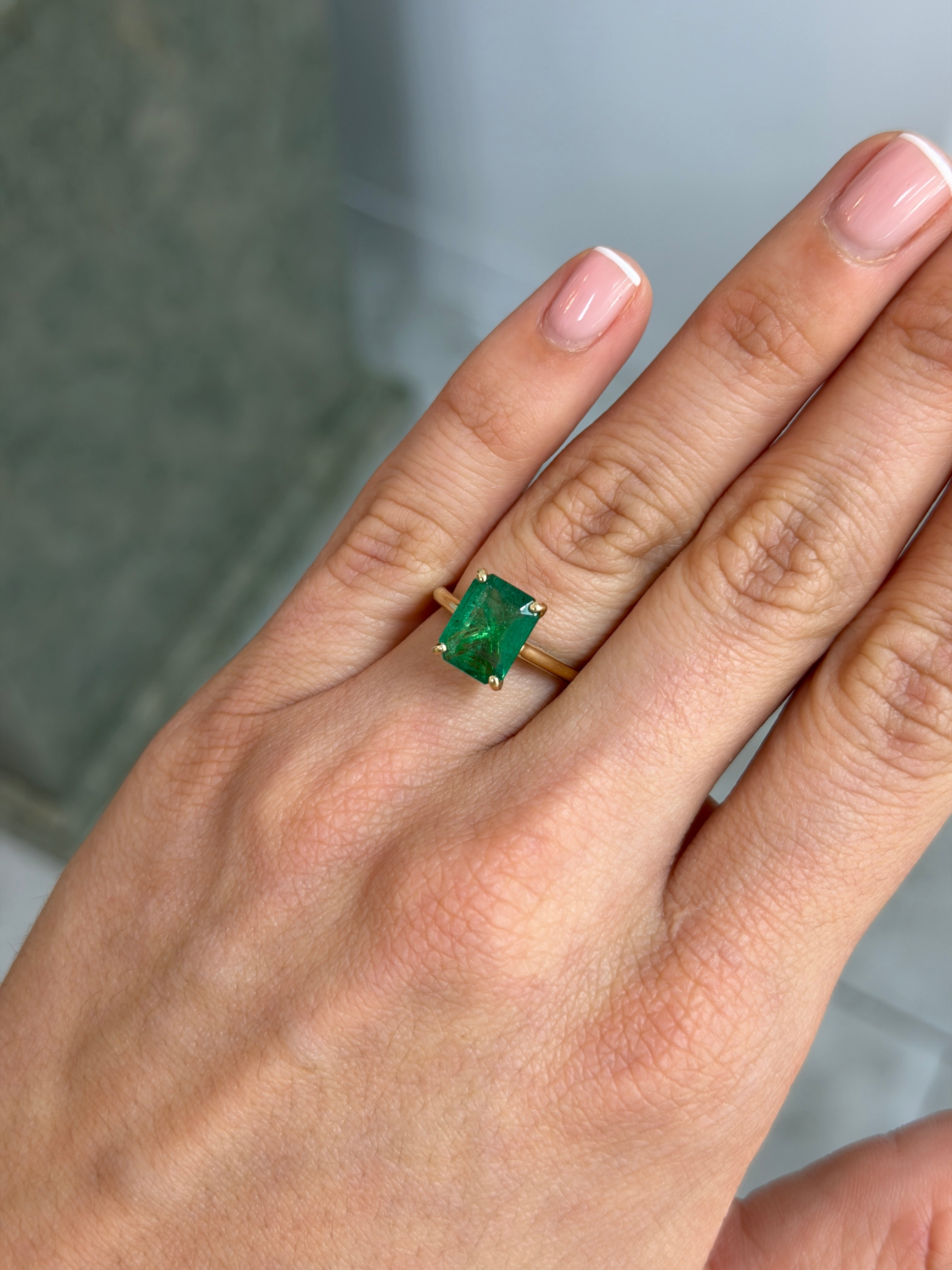 14K gold emerald cut emerald engagement ring with hidden diamonds and gallery setting, featuring 3.20 carats of natural emeralds.