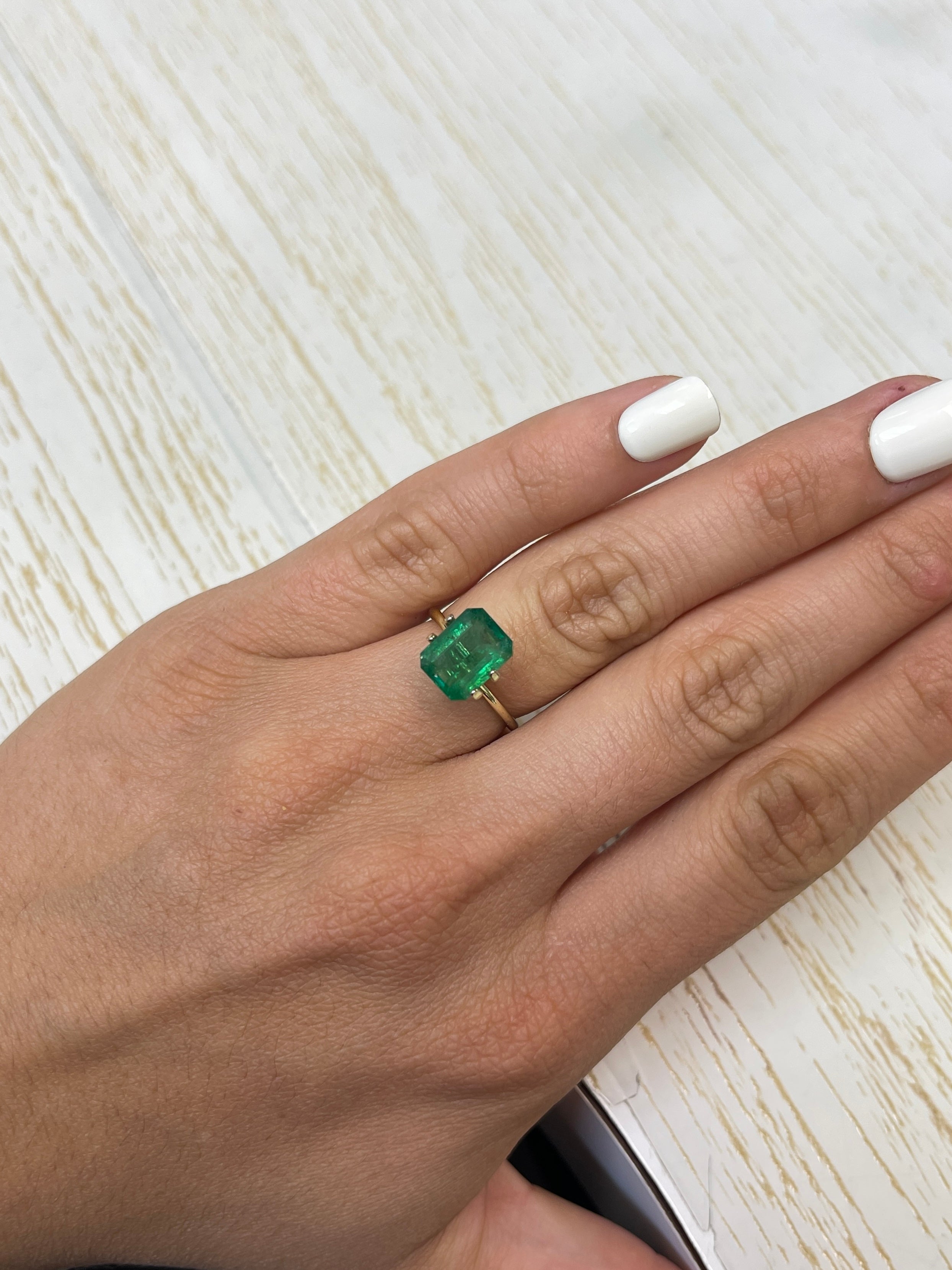 3.31 carat mossy green natural Zambian emerald in an emerald cut, showcasing its vibrant color and clarity.