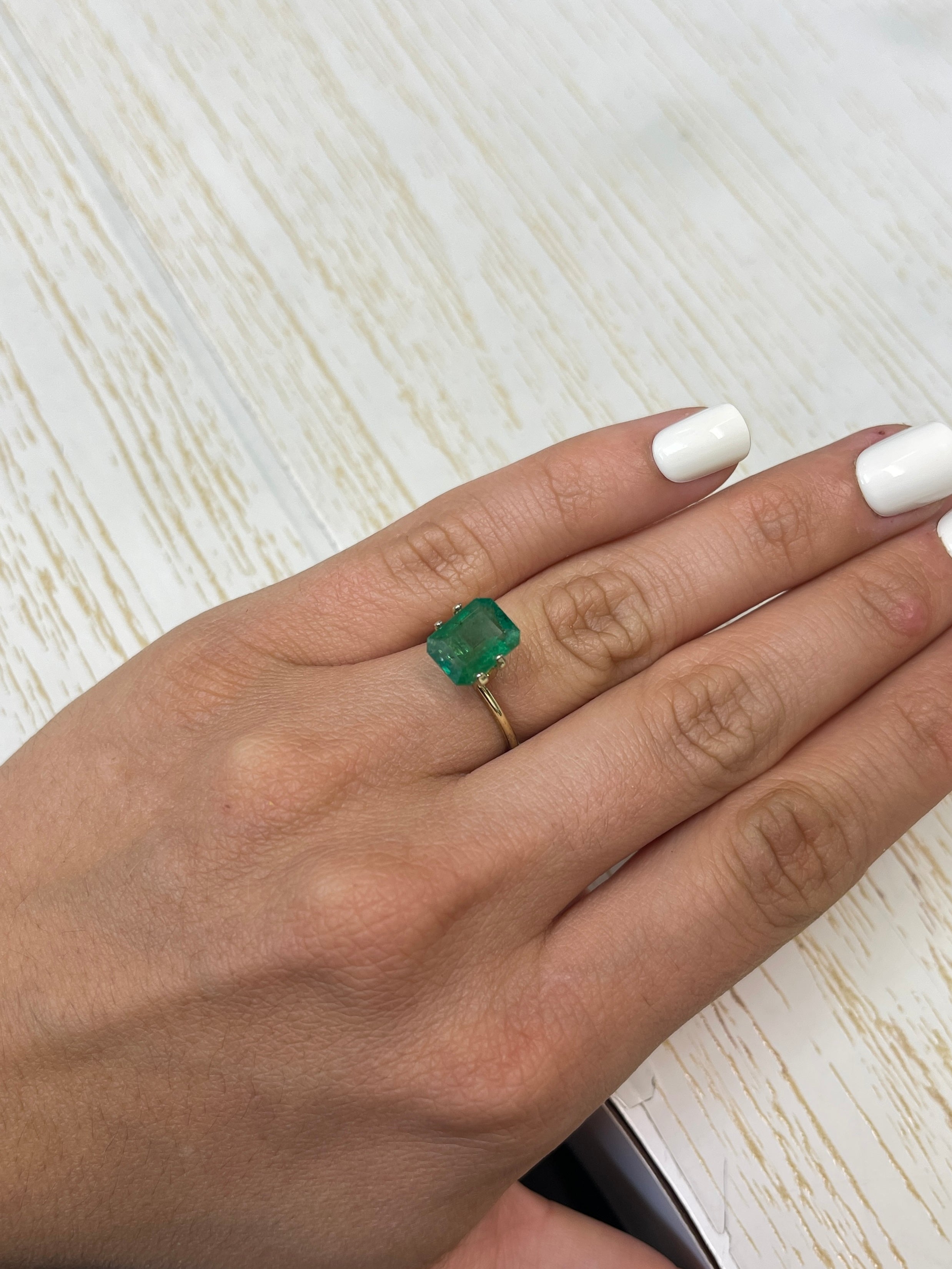 3.31 carat mossy green natural Zambian emerald loose gemstone in an emerald cut, showcasing rich green color and clarity.