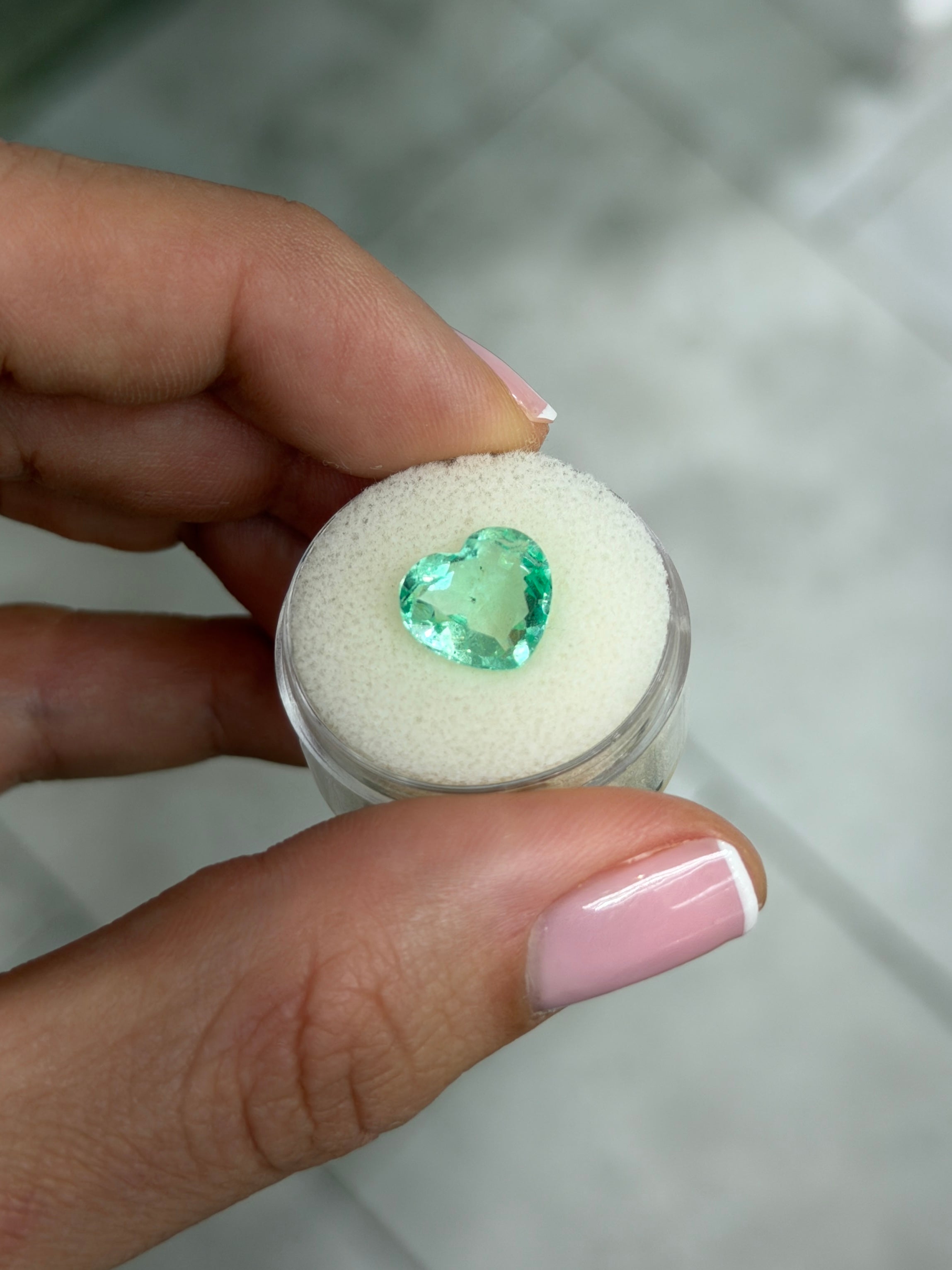 Light bluish-green 3.44 carat Colombian emerald heart-shaped loose gemstone with natural freckles, 10x11 portrait cut by JR Colombian Emeralds.