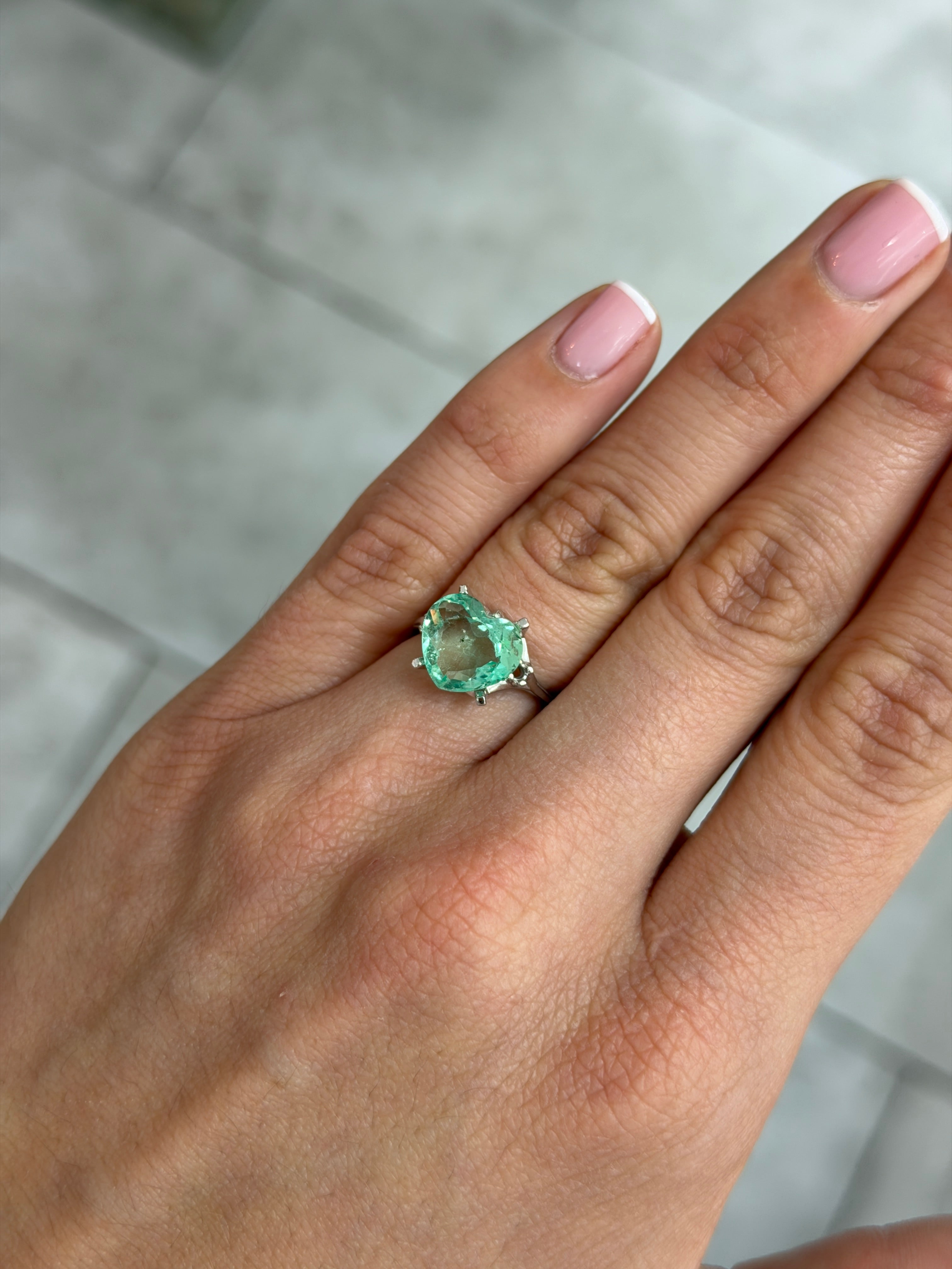 3.44 carat light bluish-green Colombian emerald in heart shape with natural freckles, 10x11 portrait cut, loose gemstone by JR Colombian Emeralds.