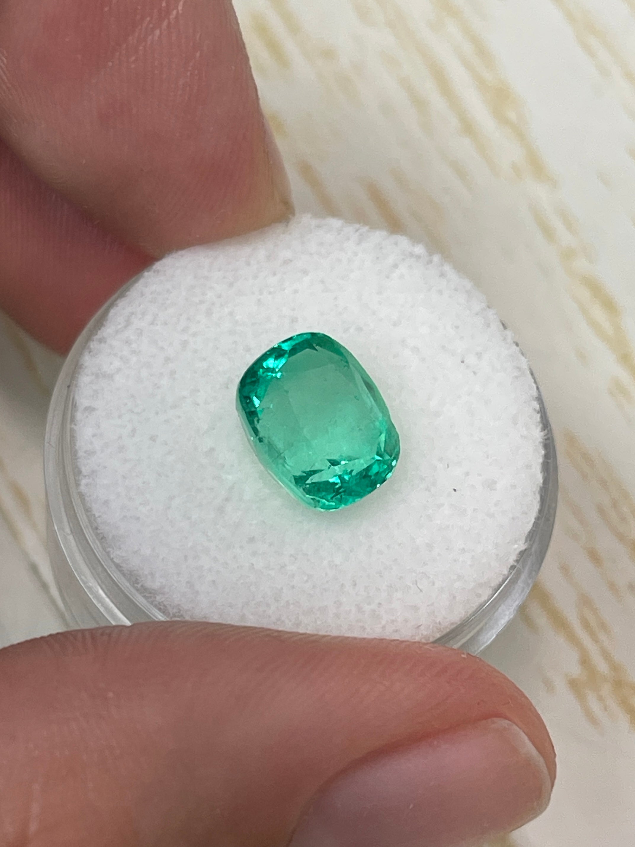 Yellowish green 3.50 carat natural Colombian emerald in cushion cut, loose gemstone displayed by JR Colombian Emeralds.
