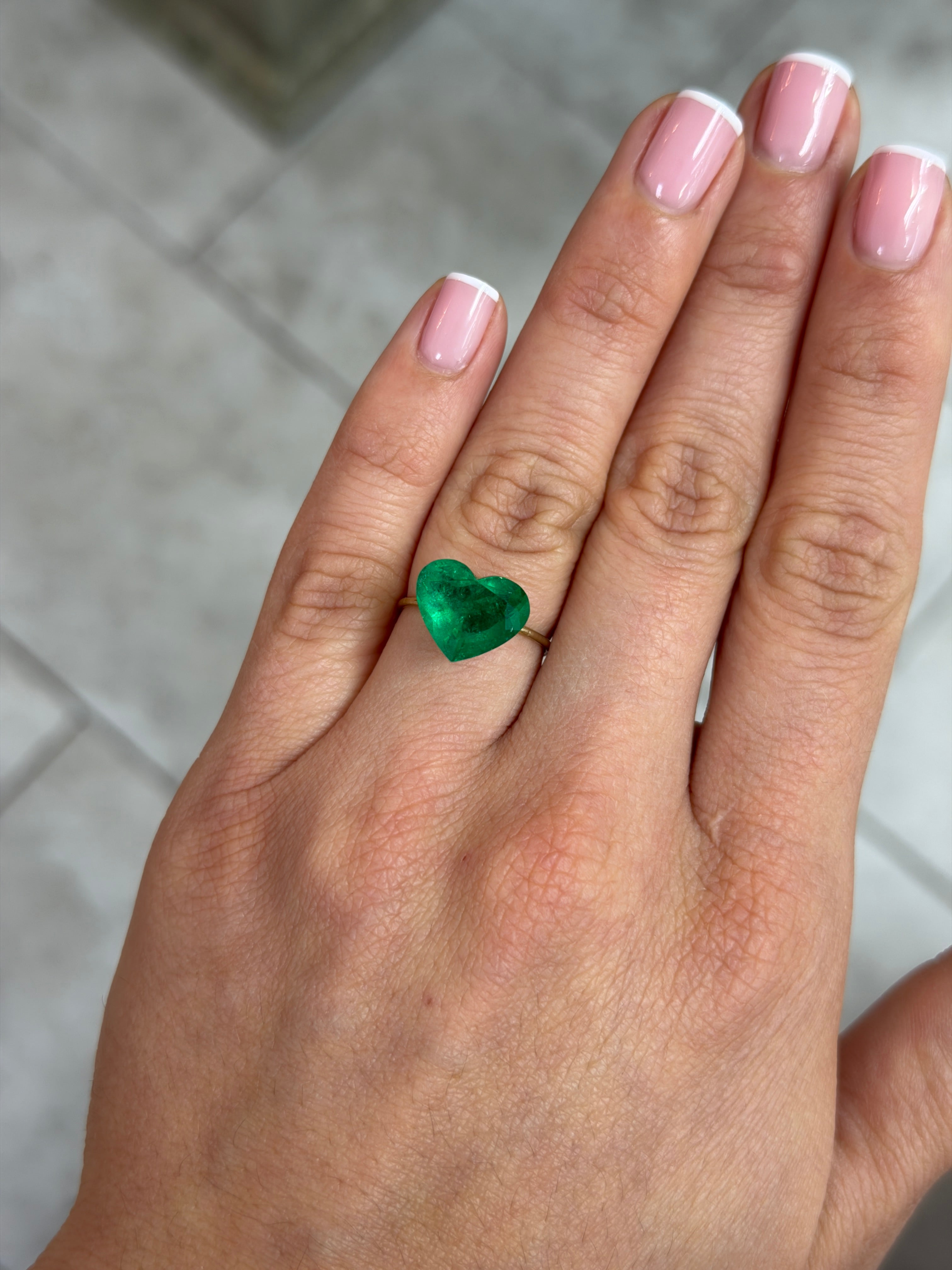 4.79 carat AAA+ intense green natural Colombian emerald loose gemstone in heart cut, displayed on a white background.