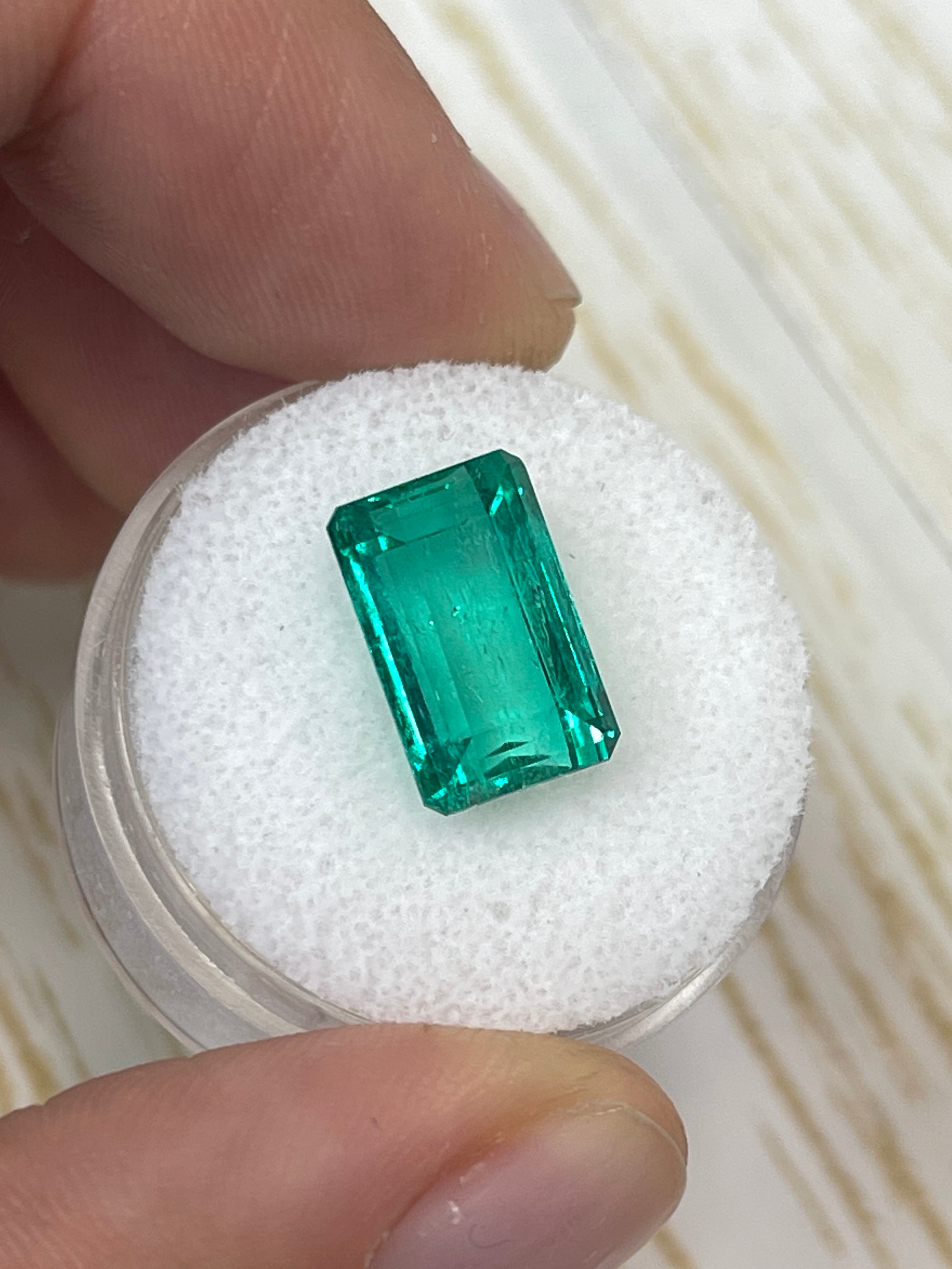 5.63 carat 13x8mm VS bluish green natural Colombian emerald in emerald cut, loose gemstone with vibrant color and clarity.