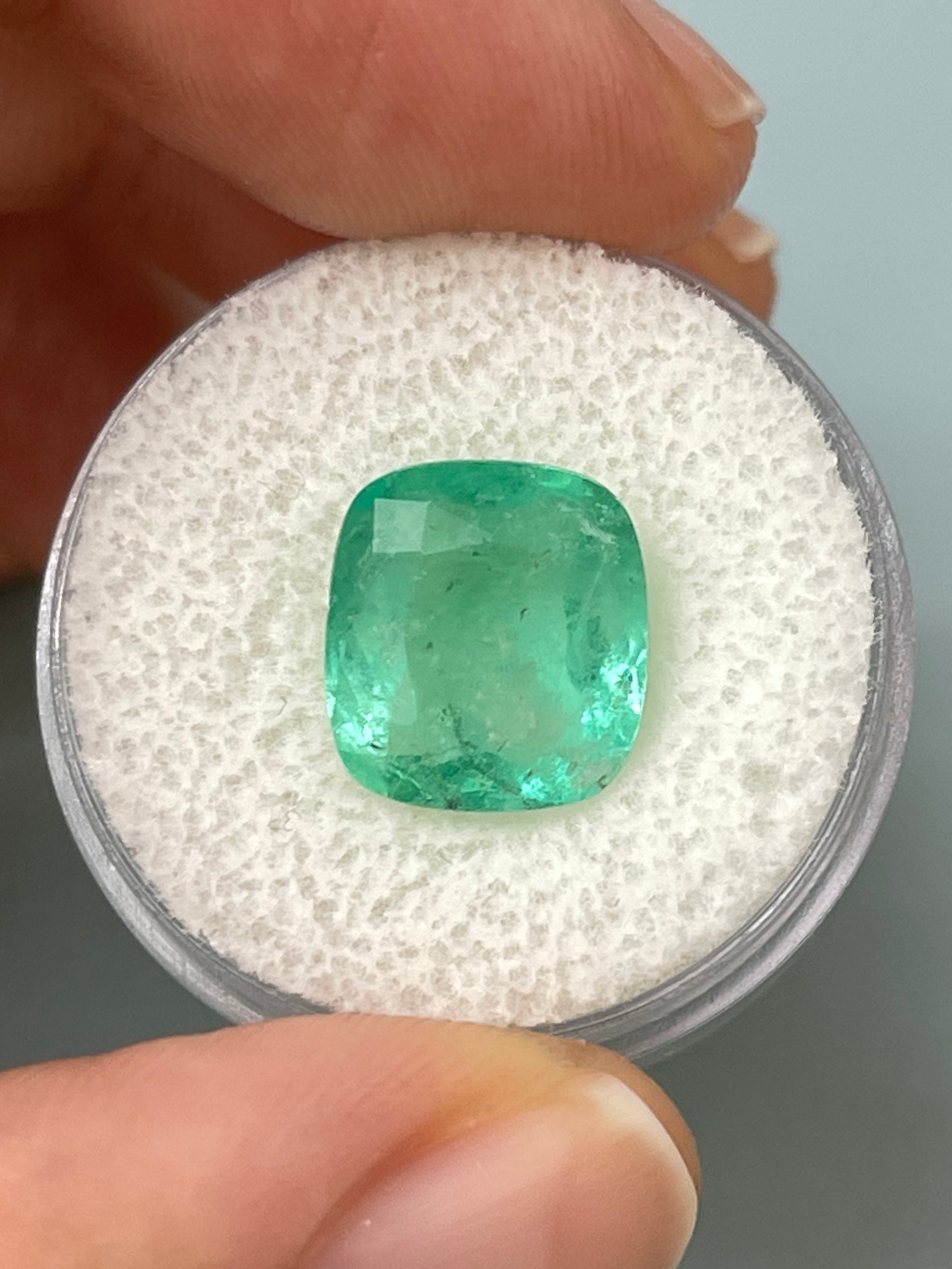 Loose 5.86 carat Colombian emerald in cushion cut with earthy pastel green color, natural gemstone from JR Colombian Emeralds.