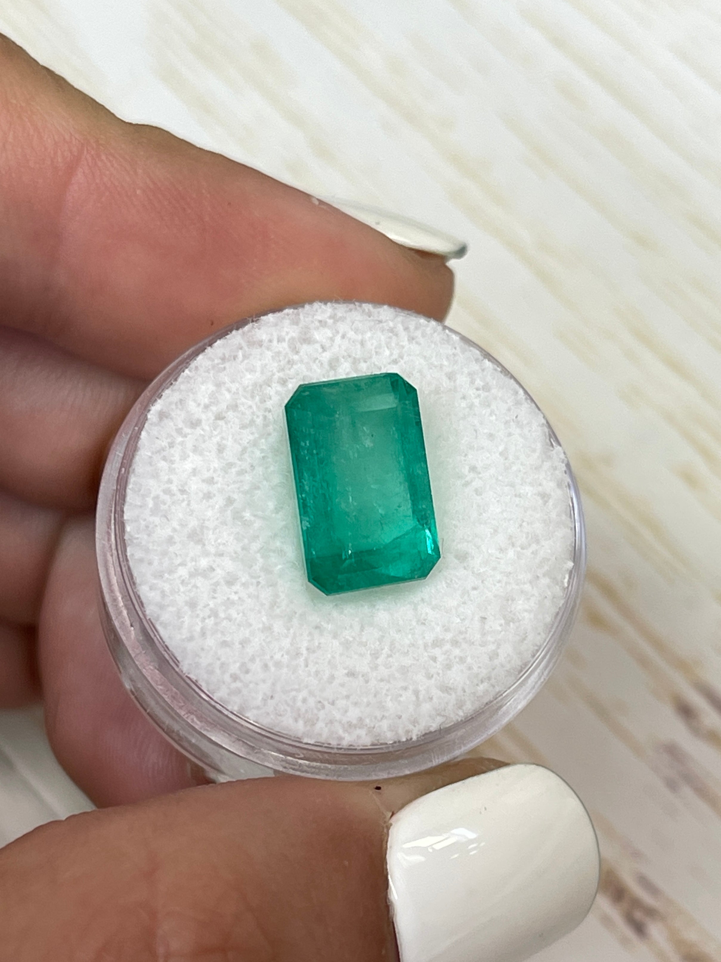 Bluish green 5.94 carat Colombian emerald loose gemstone in an emerald cut, displayed by JR Colombian Emeralds.