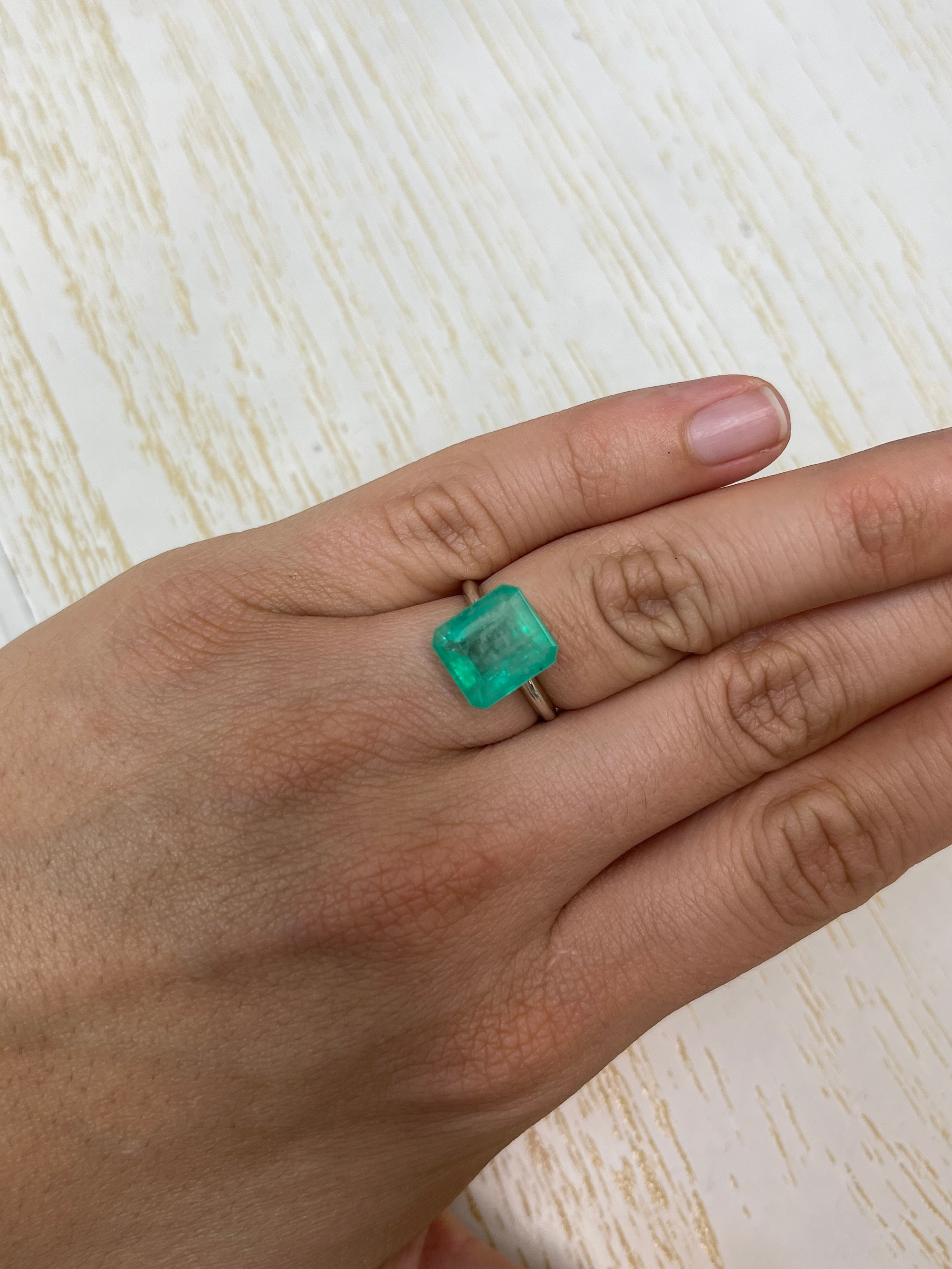 6.13-carat earthy pastel green natural Colombian emerald in an emerald cut, showcasing clarity and vibrant green color.
