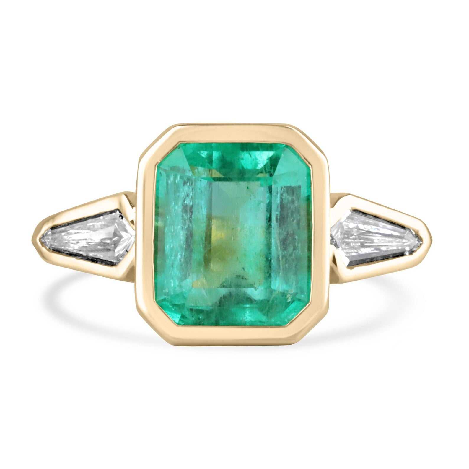 7.49tcw Colombian emerald and kite diamond three stone ring in 18K gold bezel setting.
