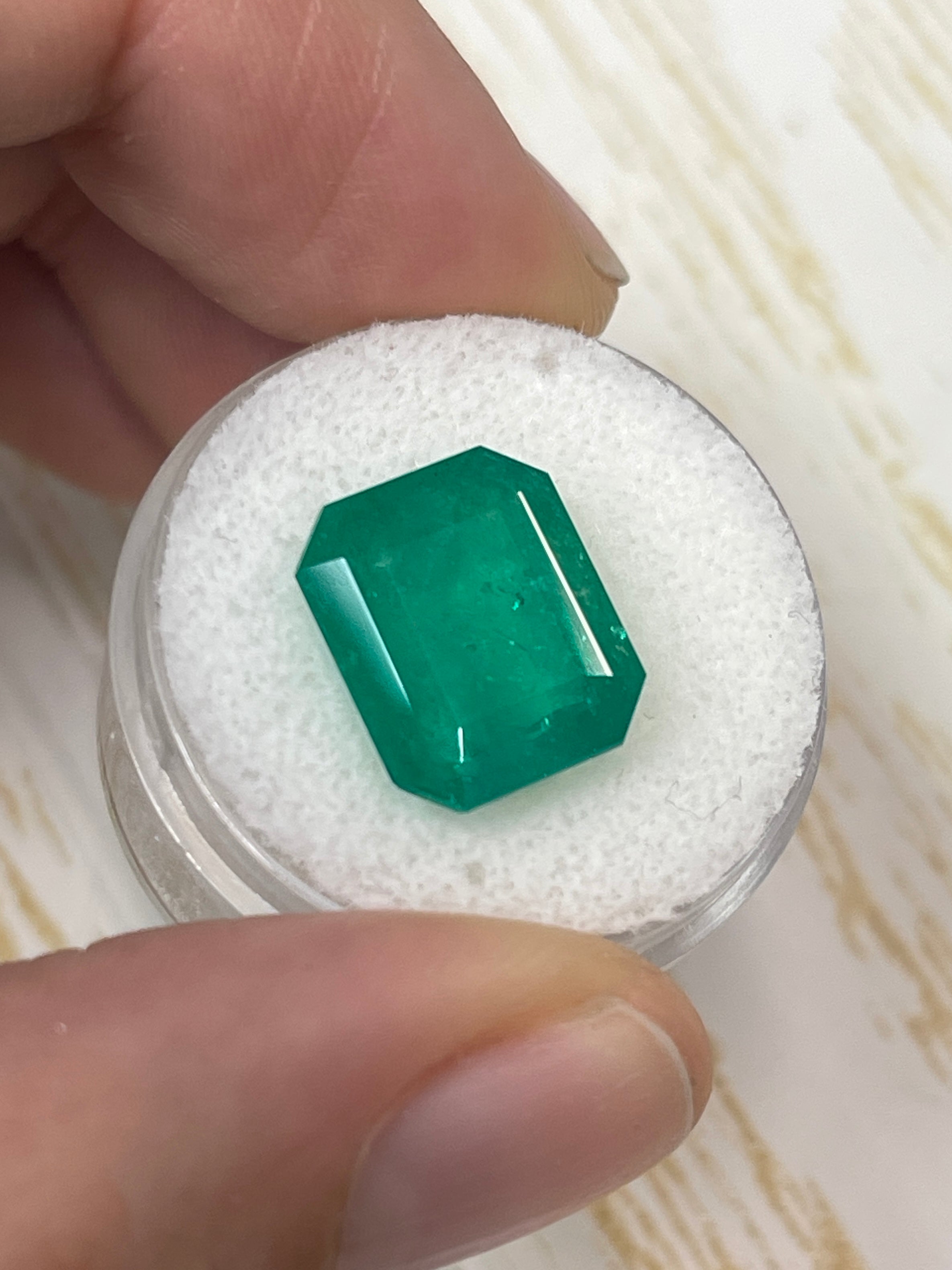 Deep forest green 7.51 carat Colombian emerald cut loose gemstone from JR Colombian Emeralds, showing its rectangular shape and faceted surface.