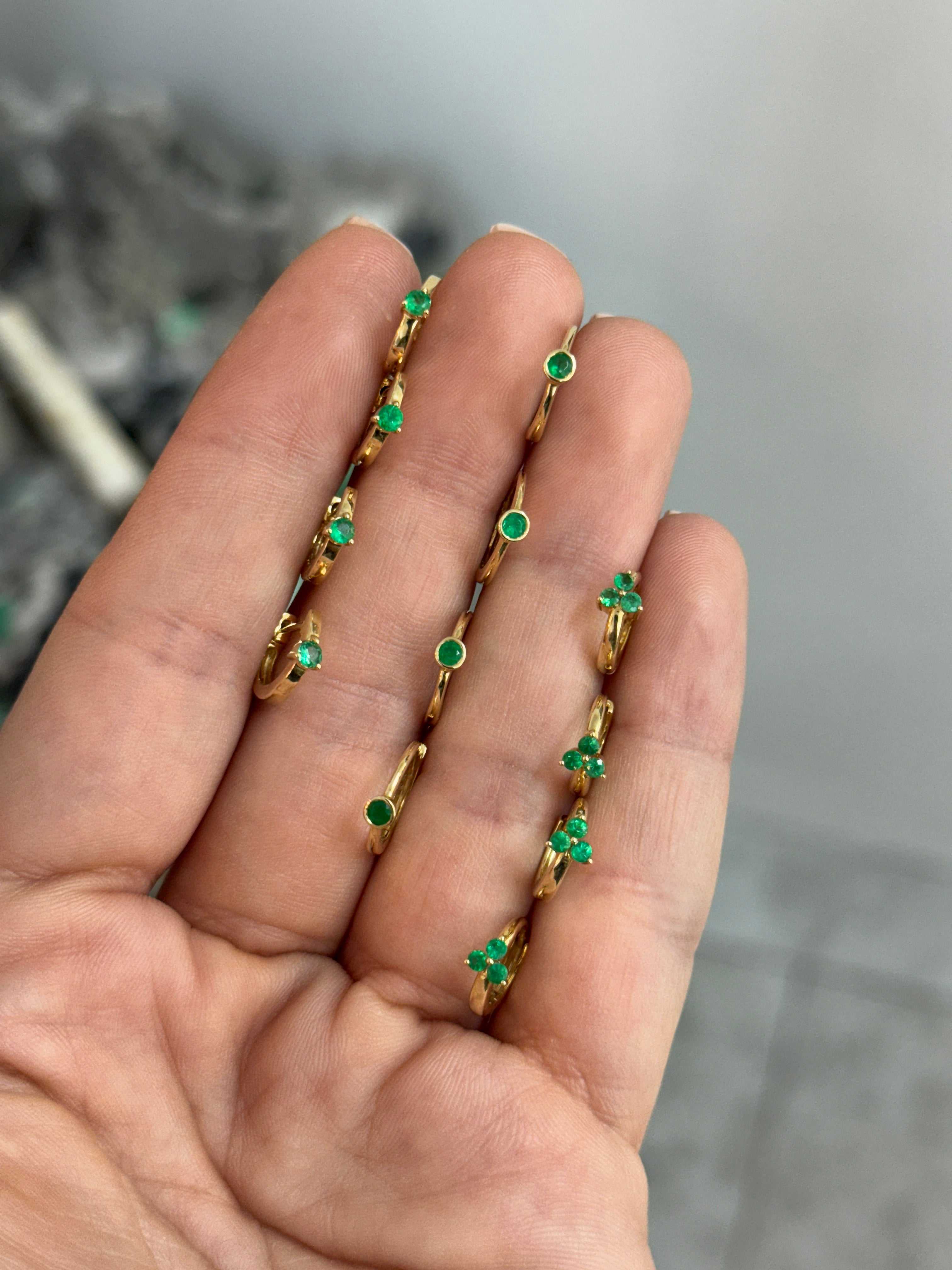 Emerald Huggie Earrings by JR Colombian Emeralds with three-prong 14K gold setting, close-up view of the jewelry.