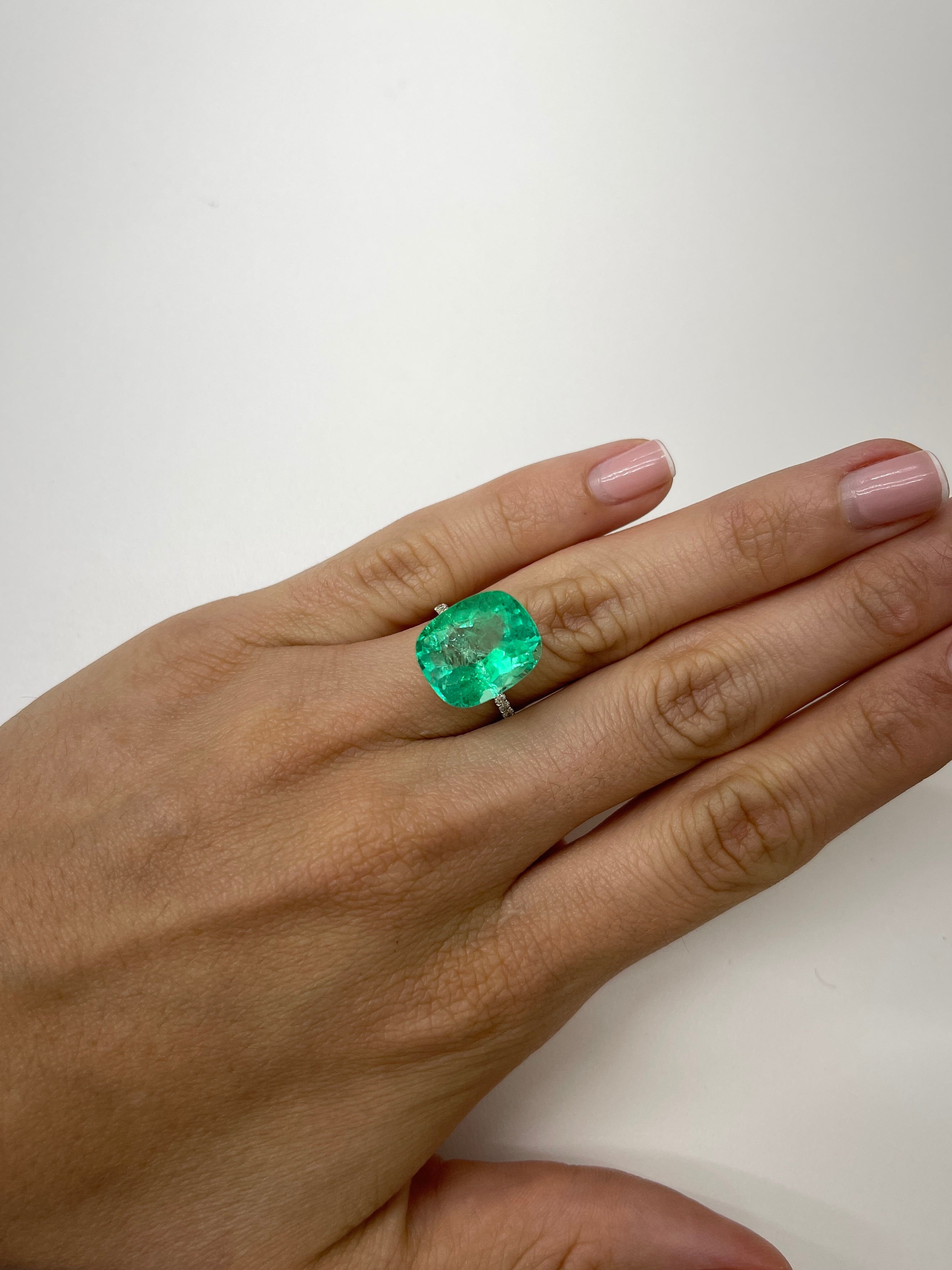 Large 11.50 carat yellowish natural cushion Colombian emerald from JR Colombian Emeralds, showcasing a vibrant, spready Muzo gemstone.