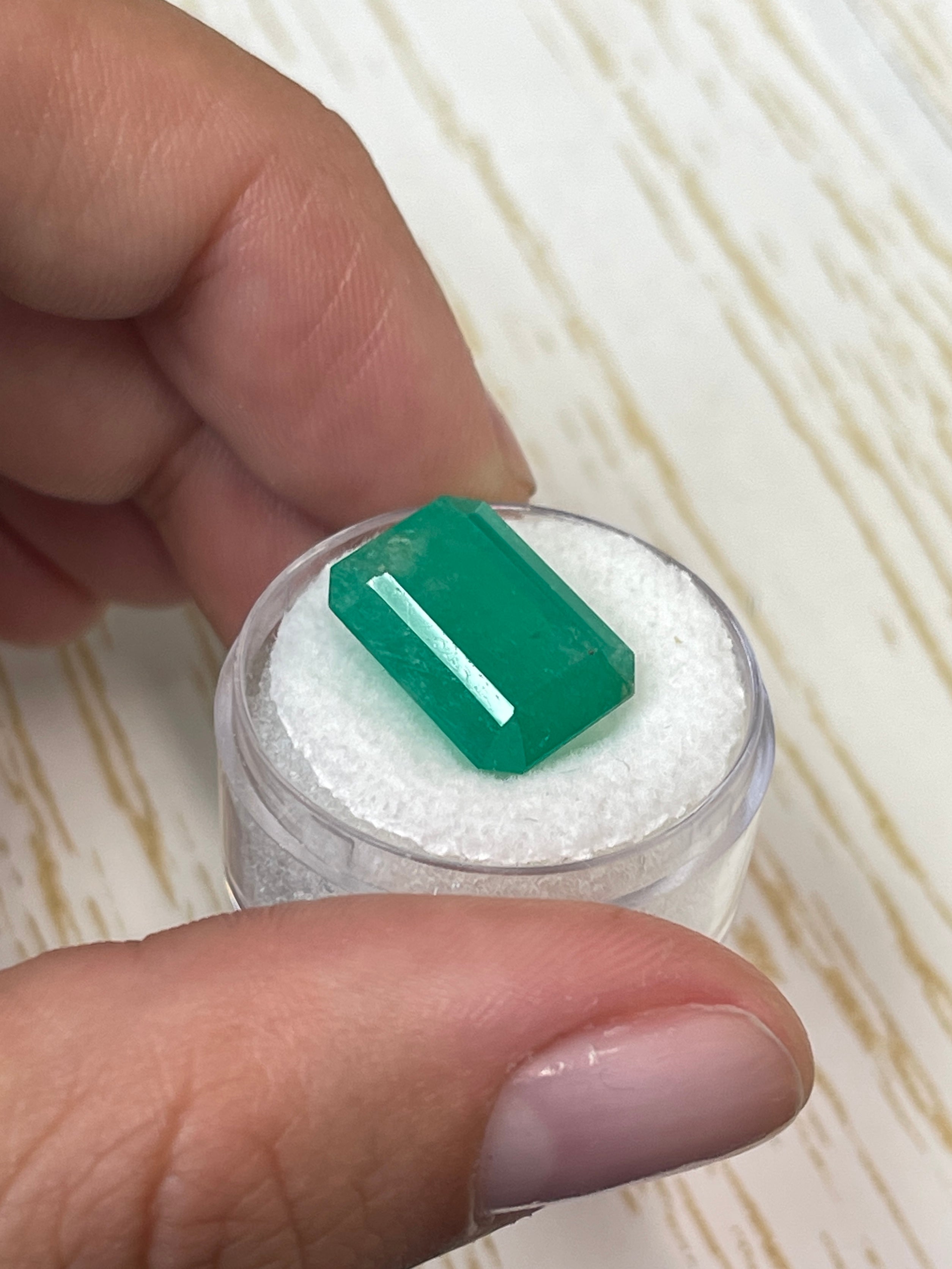 Large 12.13 carat natural Colombian emerald in an emerald cut, showcased by JR Colombian Emeralds.