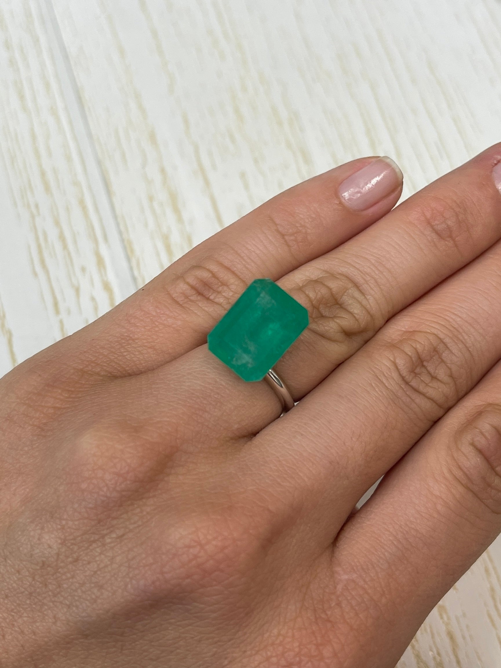 Large 12.13 carat natural Colombian emerald loose gemstone in an emerald cut, showcasing vibrant green color and clarity.