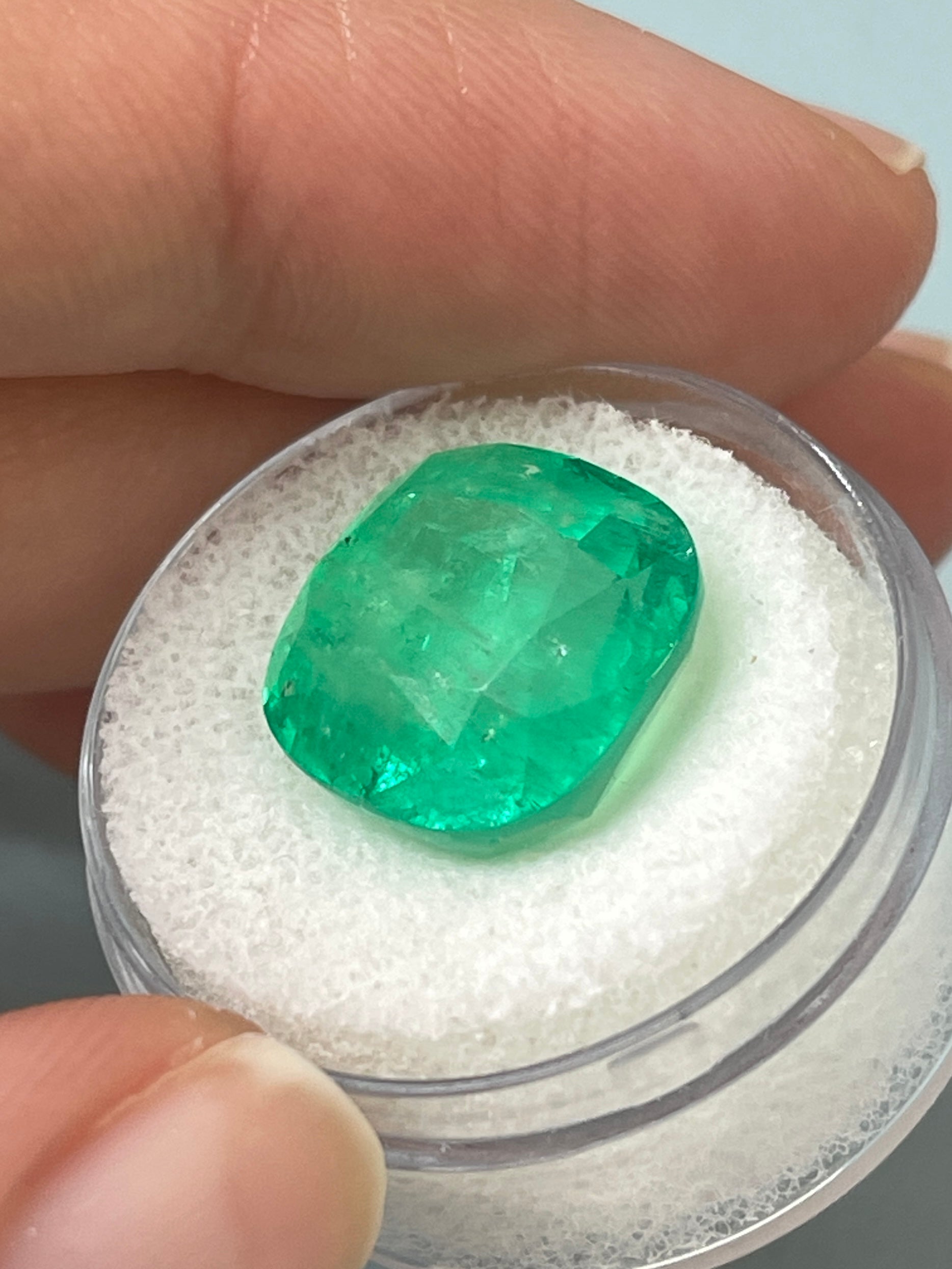 Large 12.66 carat natural cushion-cut Colombian emerald from JR Colombian Emeralds, showcasing vibrant green color and clarity.